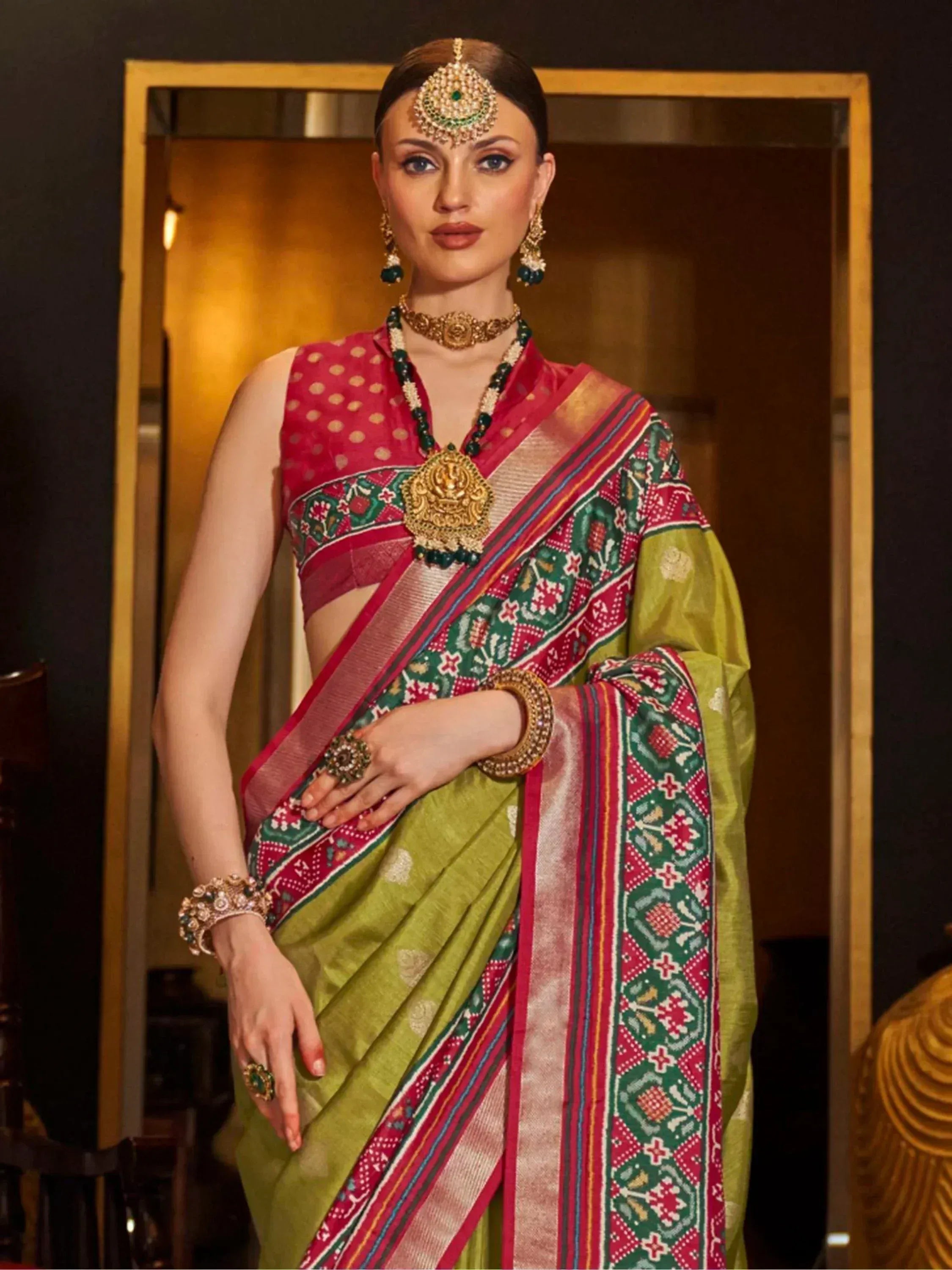Woman in green and red printed saree with gold jewelry, traditional Indian ethnic wear
