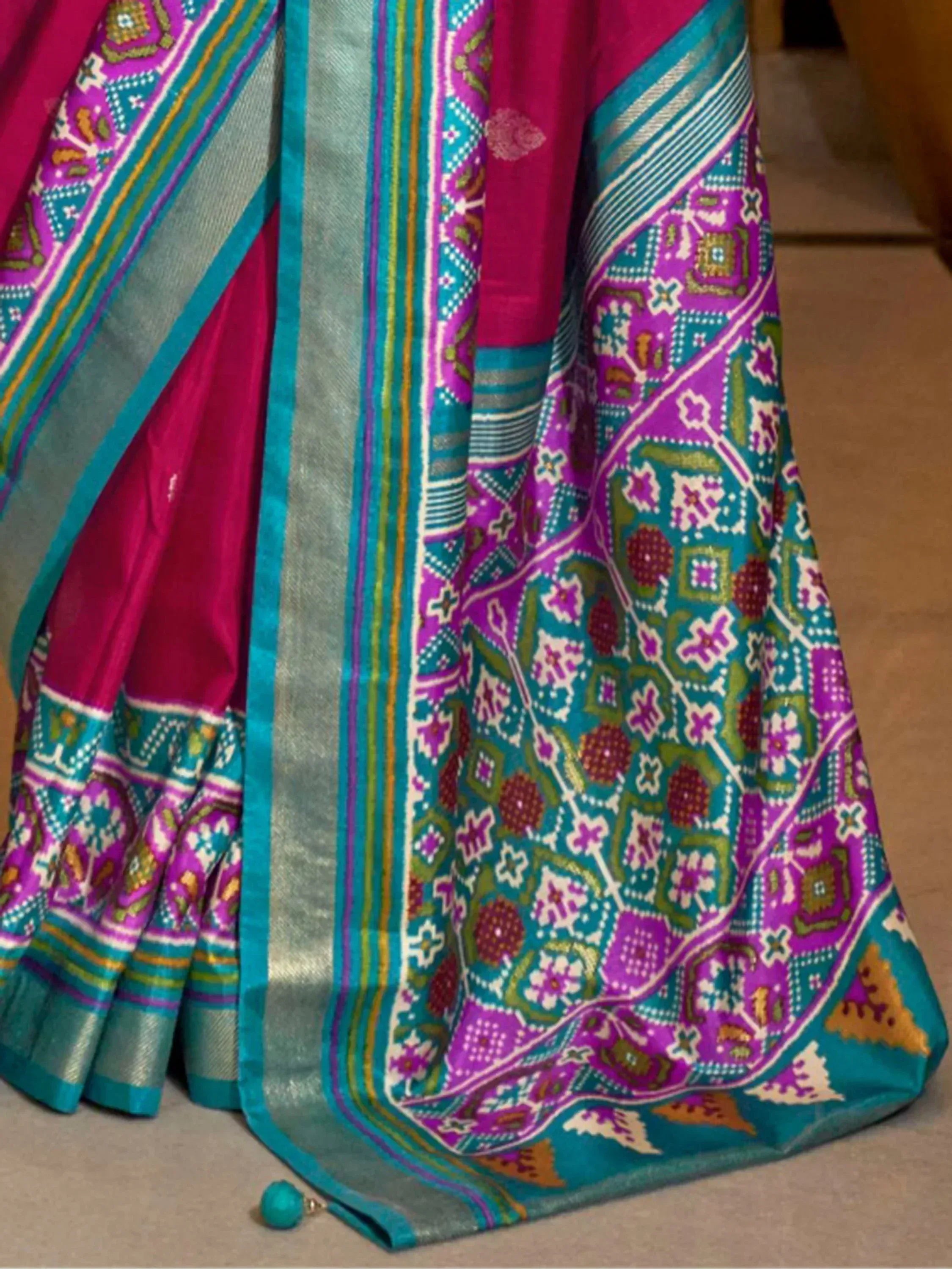 Vibrant pink and teal Indian saree with intricate geometric and floral patterns, perfect for ethnic wear.