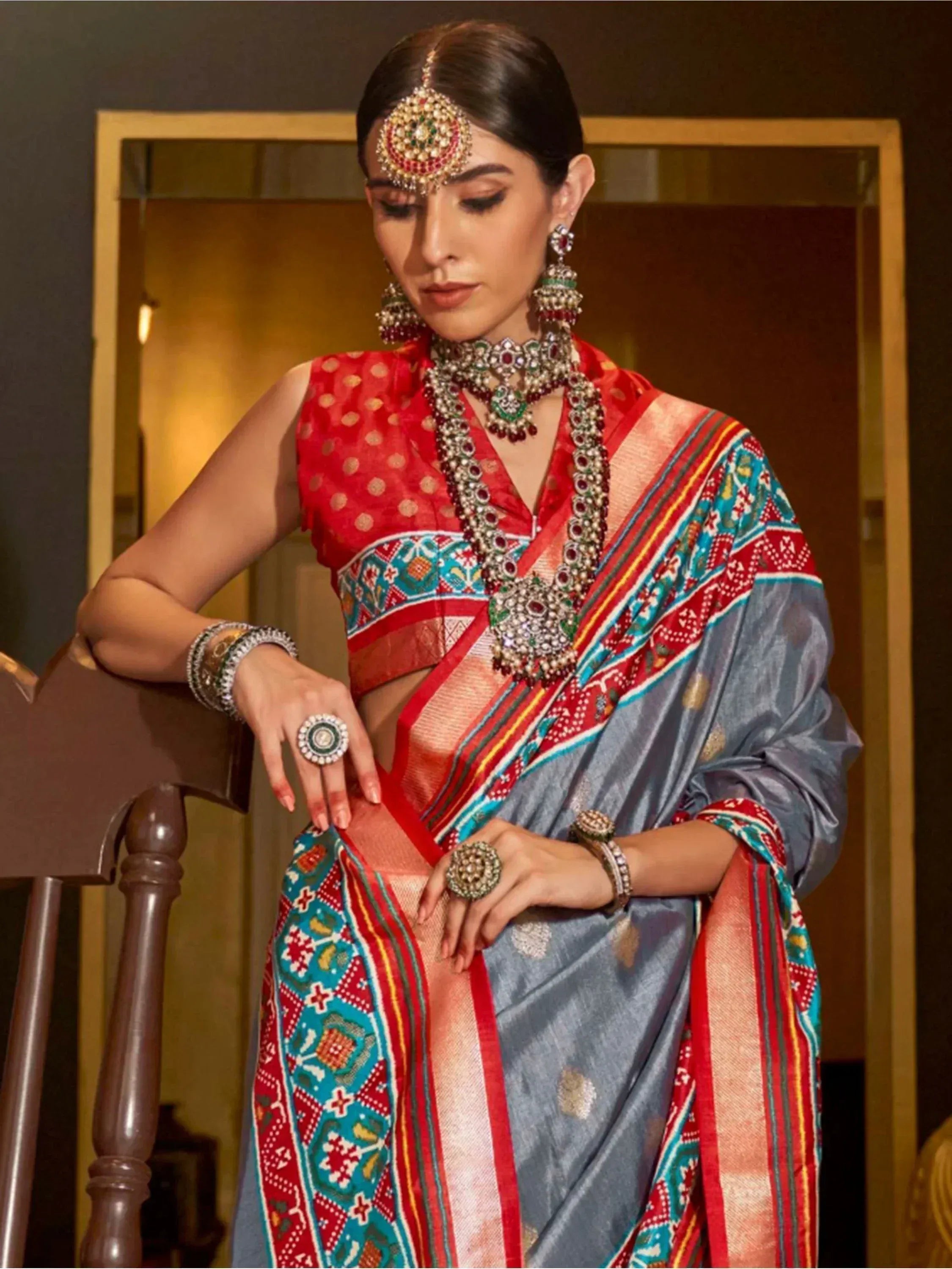 Woman in vibrant ethnic saree with red blouse, intricate jewelry, and traditional Indian attire