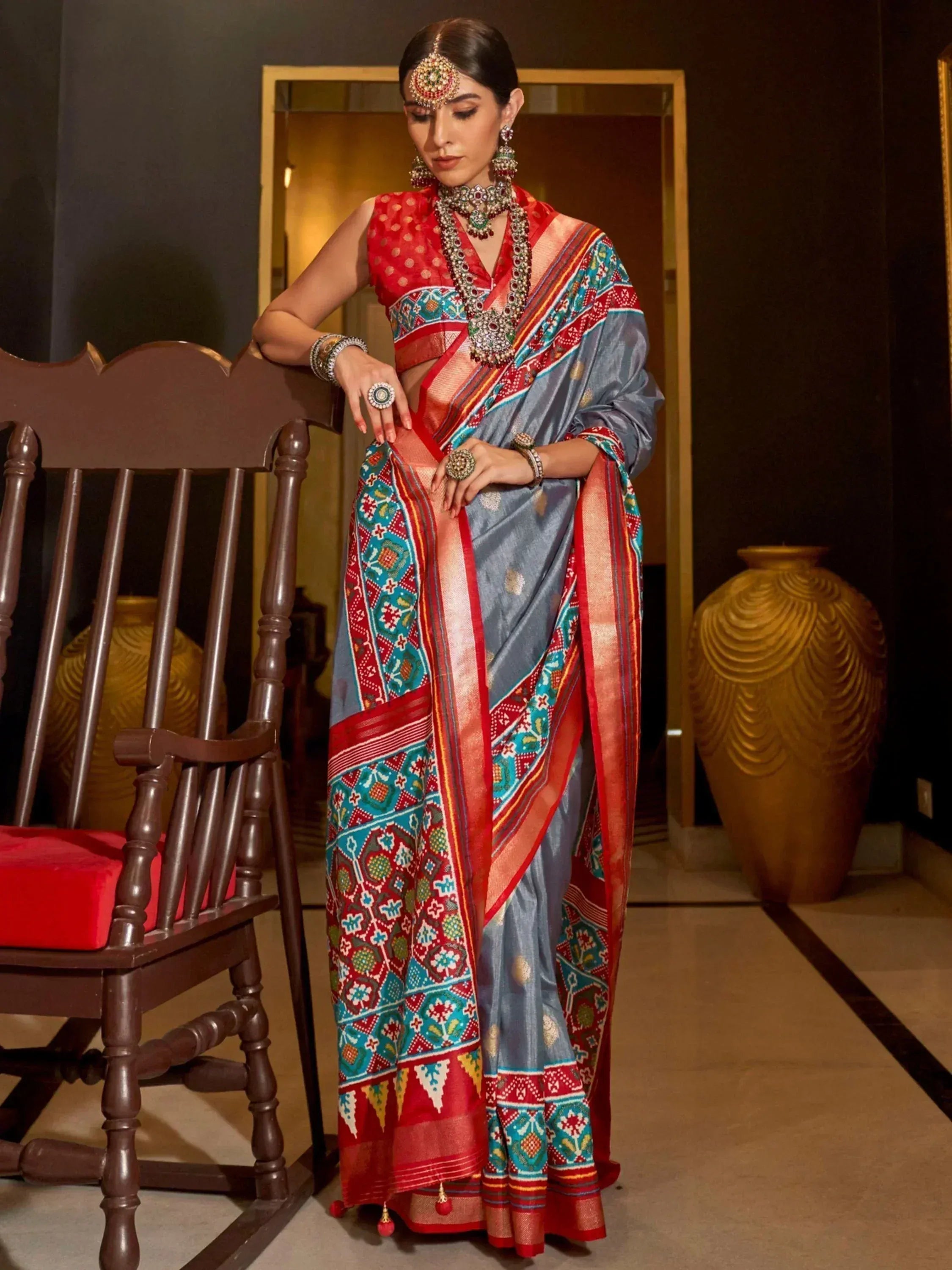 Woman in blue and red printed saree with ethnic jewelry, styled for Indian occasions