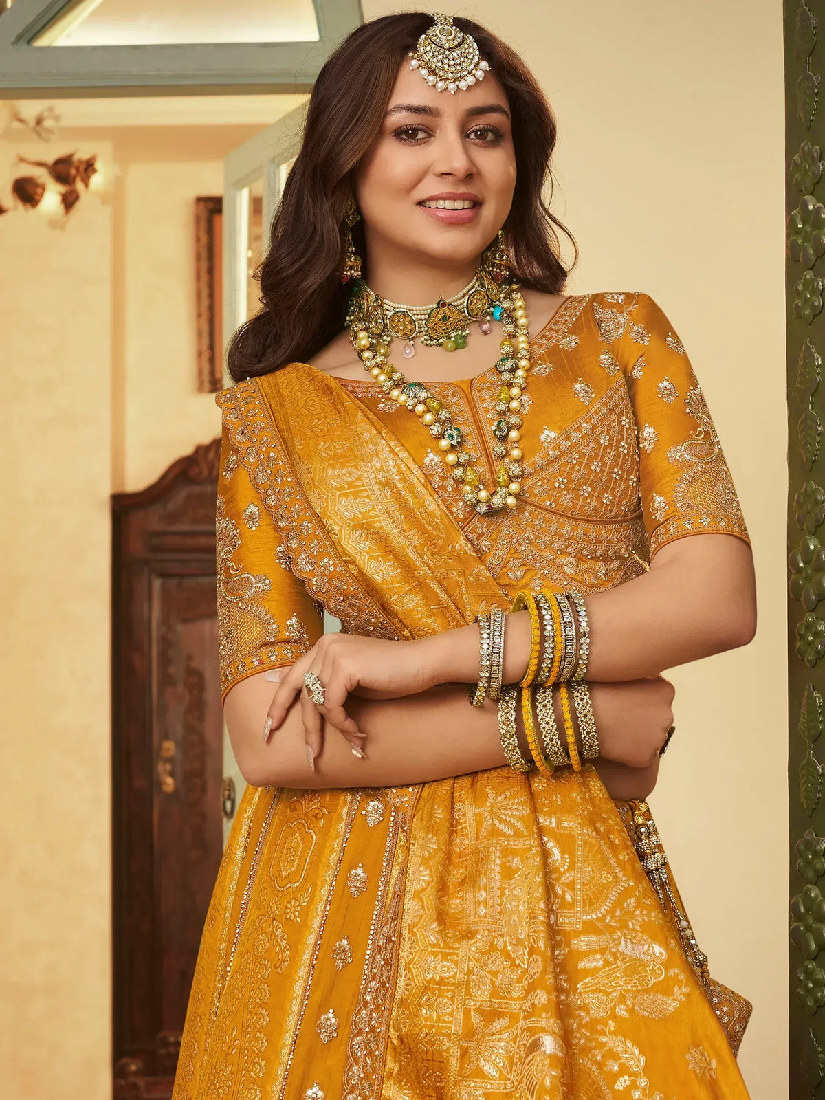 Elegant mustard yellow lehenga choli with intricate gold embroidery and traditional Indian jewelry