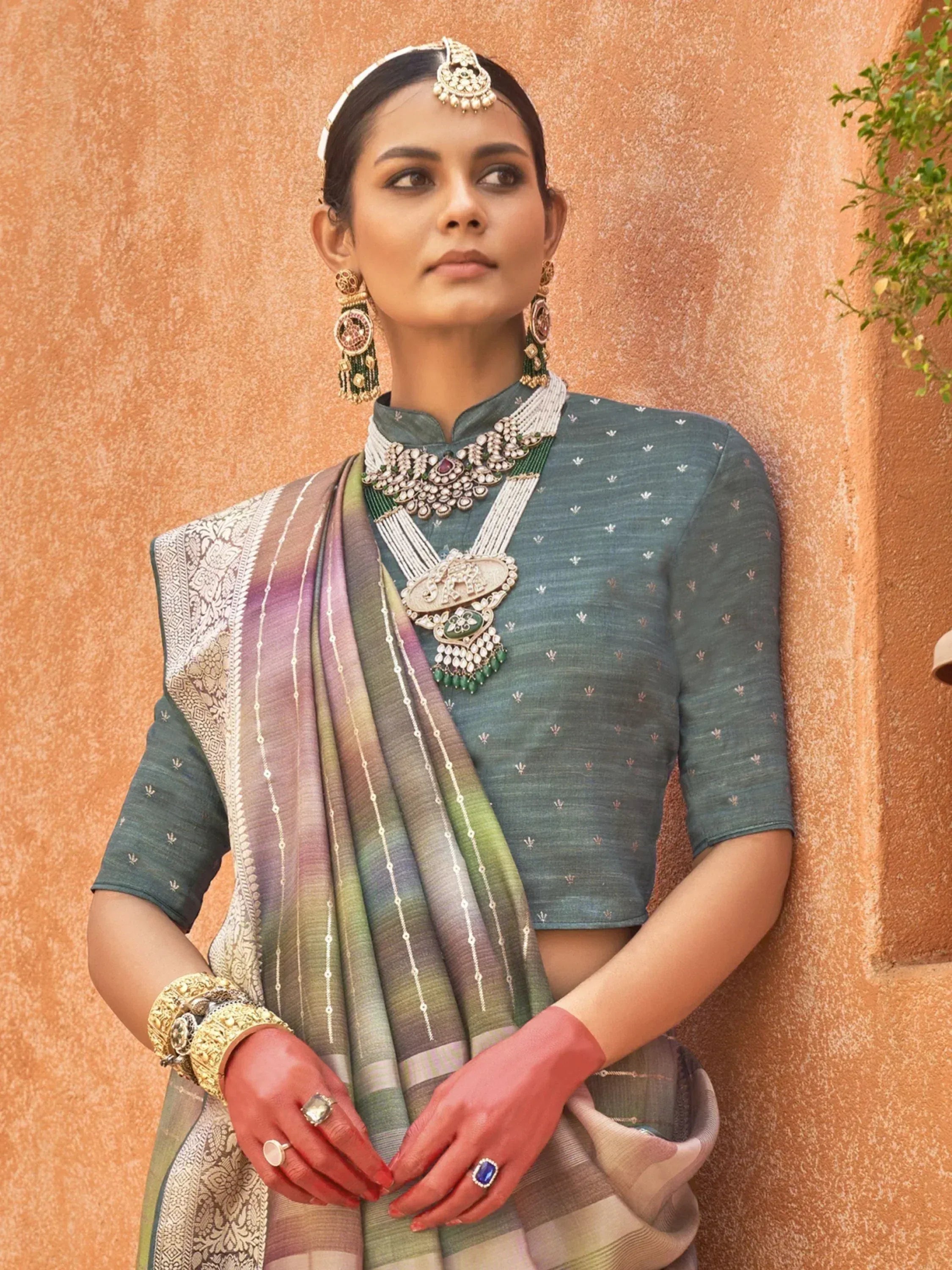 Woman in teal embroidered blouse with ombre saree, traditional Indian jewelry, and maang tikka
