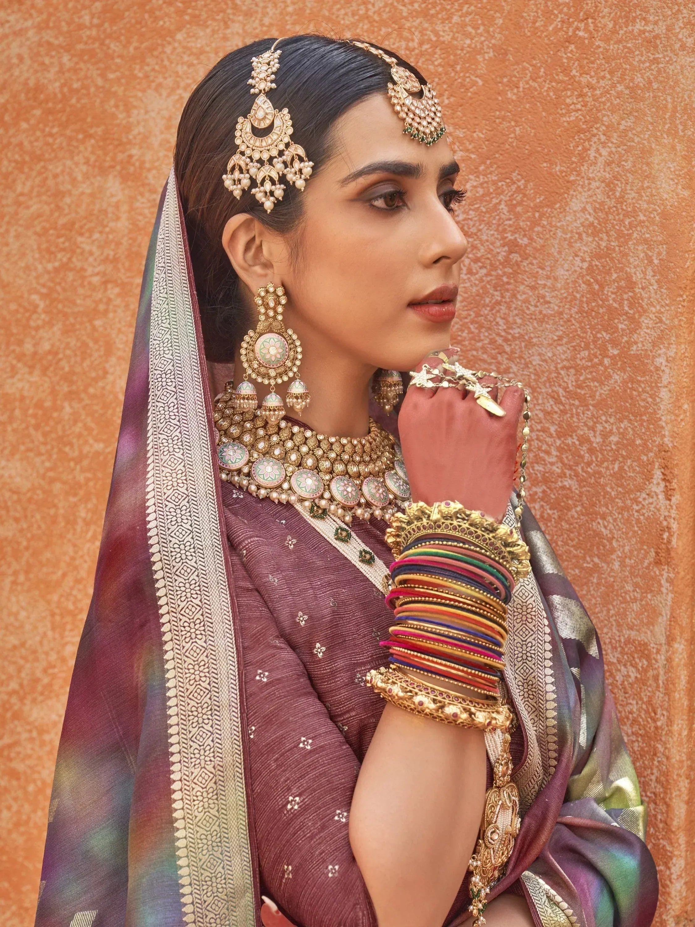 Indian bride in maroon lehenga with gold jewelry and colorful bangles, traditional ethnic wear