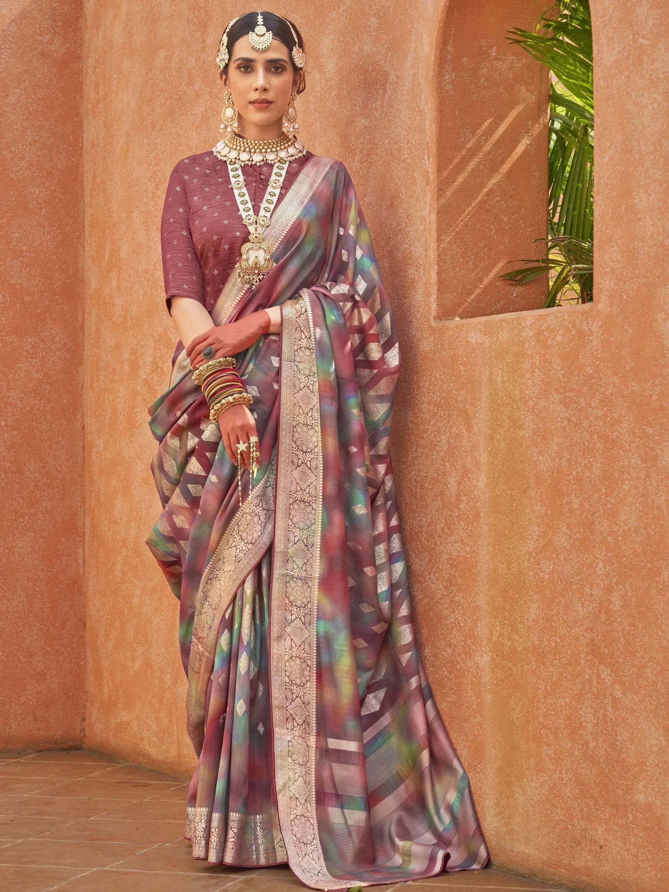 Woman in elegant Indian saree with geometric print and gold border, styled with traditional jewelry for ethnic wear.