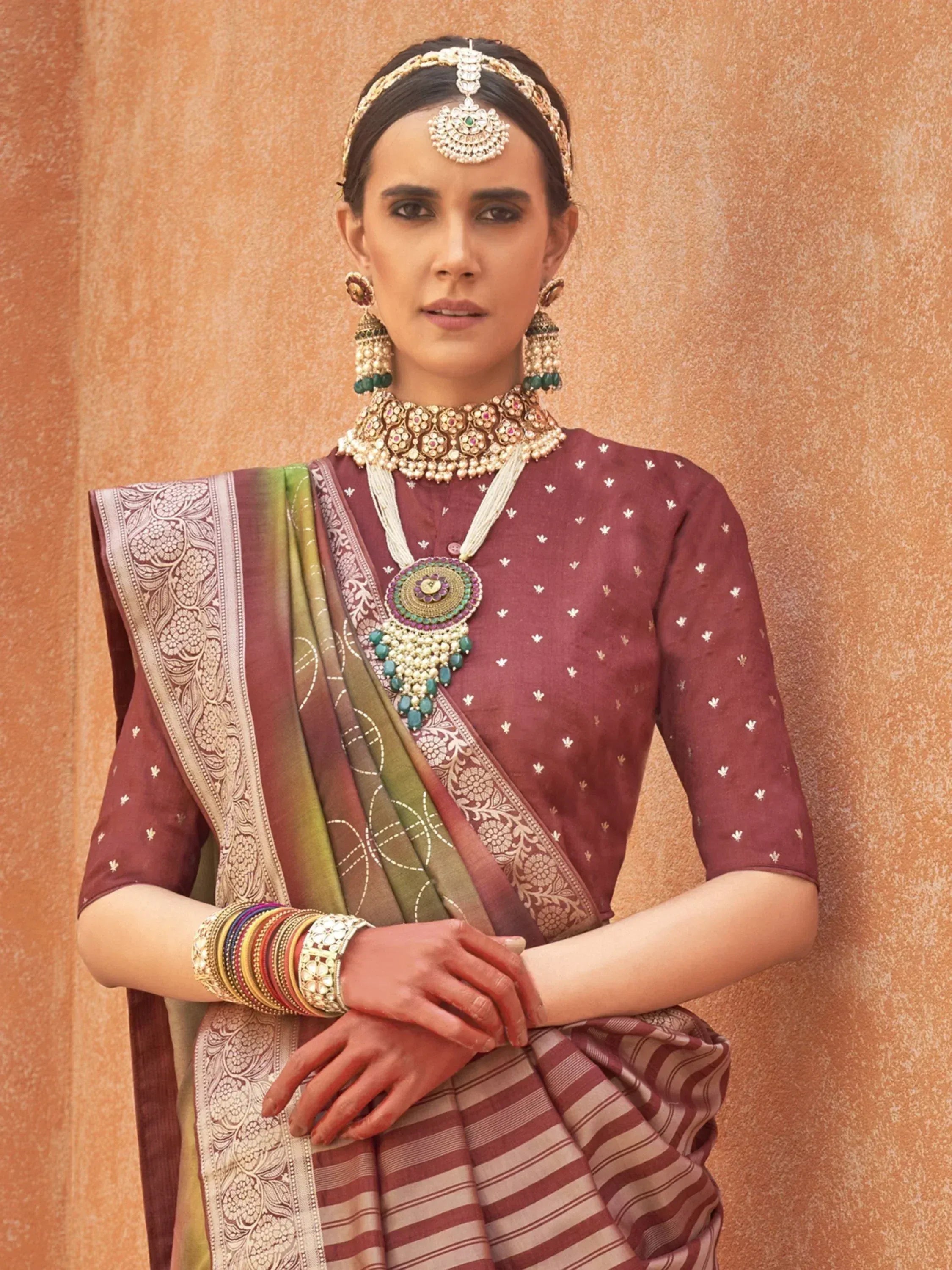 Woman in maroon ethnic saree with gold embroidery, traditional jewelry, and bangles, styled for Indian occasions