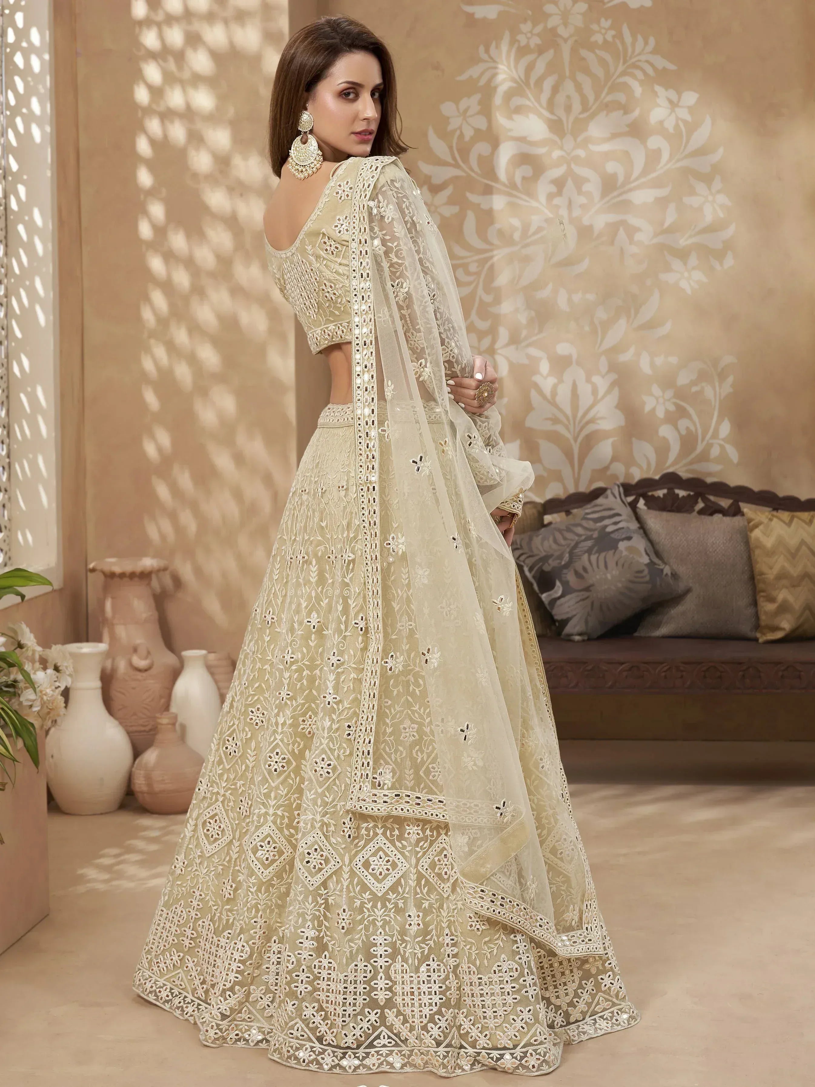 Elegant beige embroidered lehenga choli with mirror work and sheer dupatta, perfect for Indian ethnic occasions.