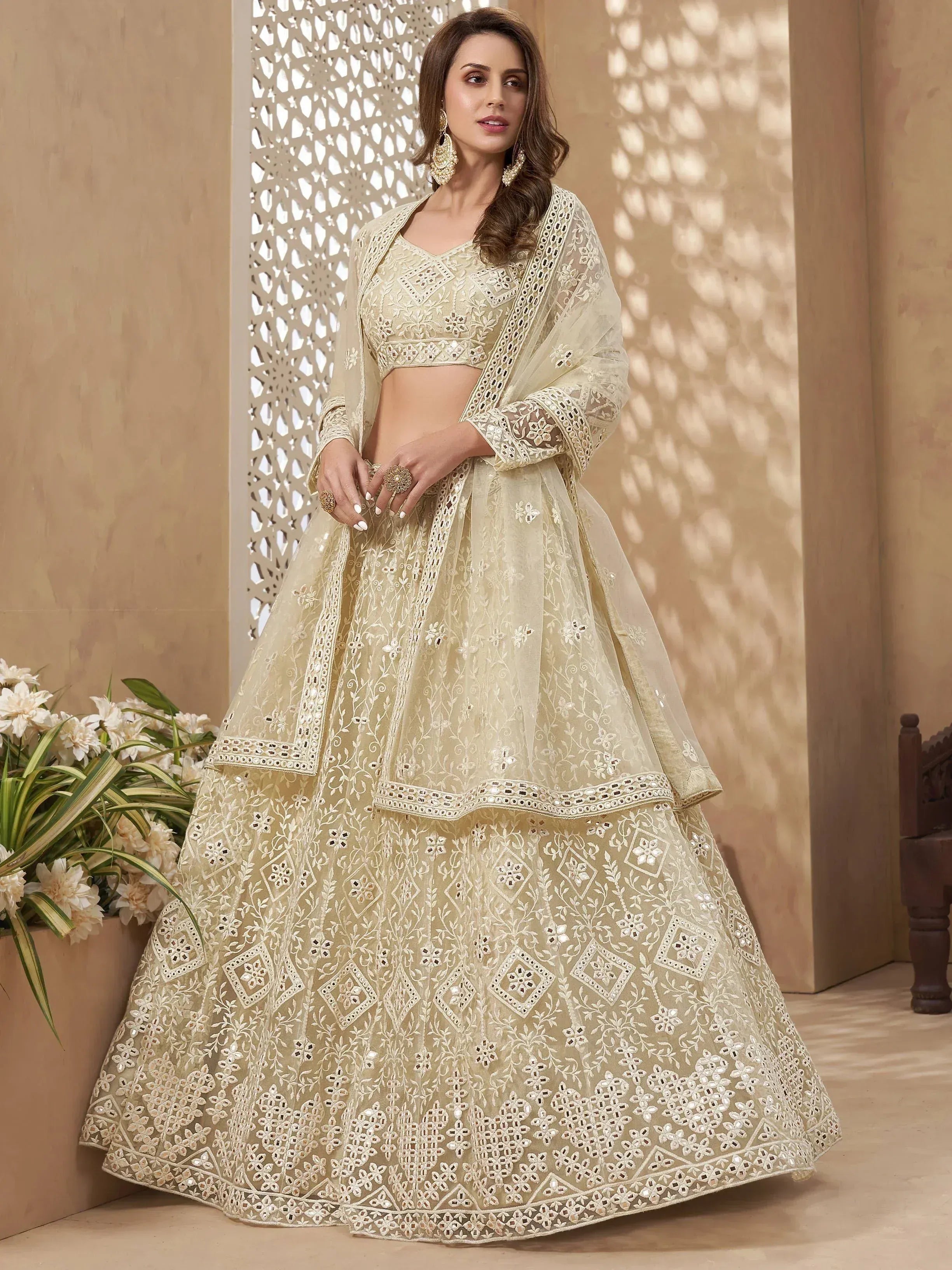 Elegant beige designer lehenga choli with intricate embroidery and mirror work, perfect for weddings and festive occasions.