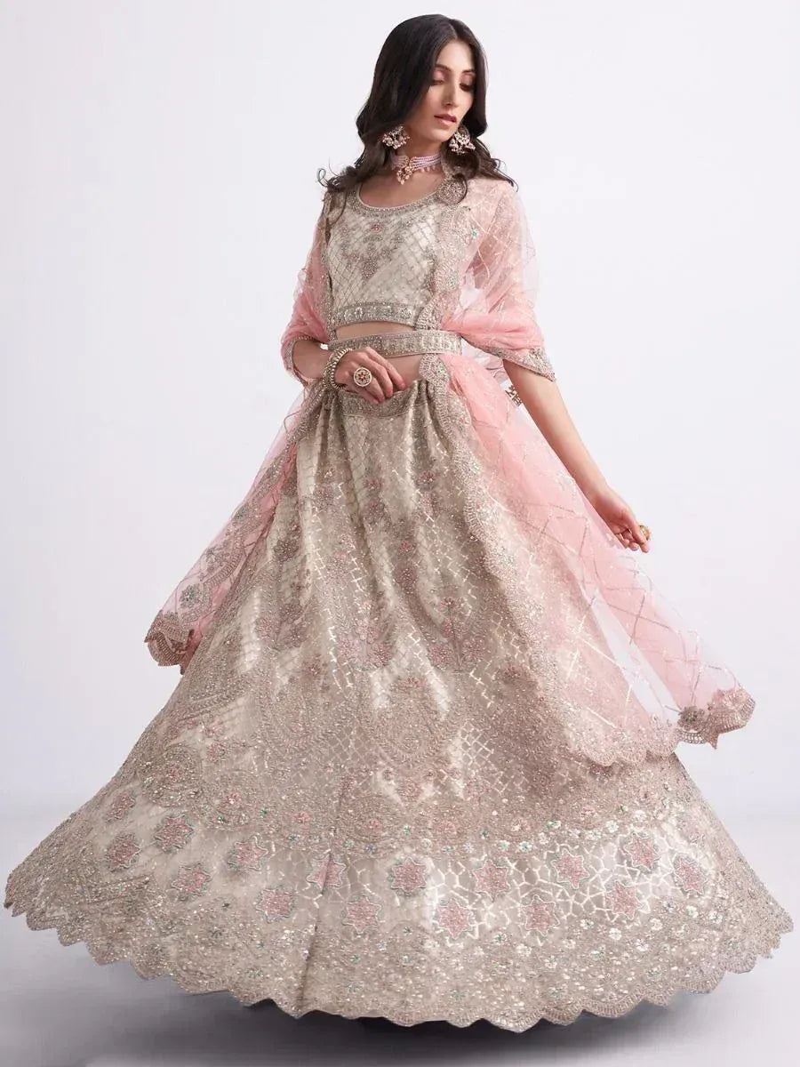 Elegant beige and pink embroidered lehenga choli with sheer dupatta, perfect for weddings and festive occasions.