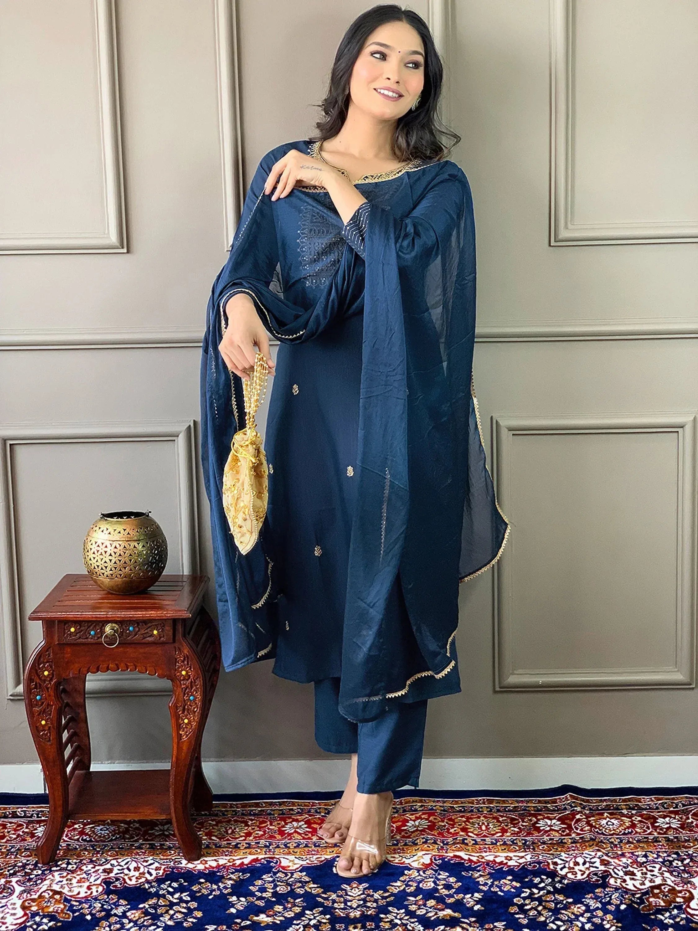 Navy blue ethnic salwar kameez with gold embroidery, paired with matching dupatta and potli bag for festive occasions