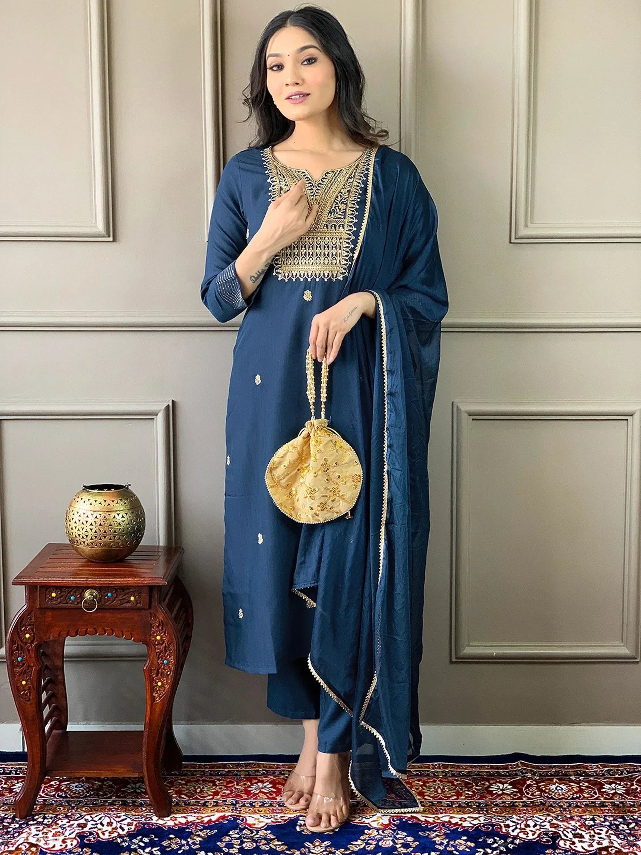 Navy blue ethnic salwar kameez with gold embroidery, paired with matching dupatta and potli bag for festive occasions