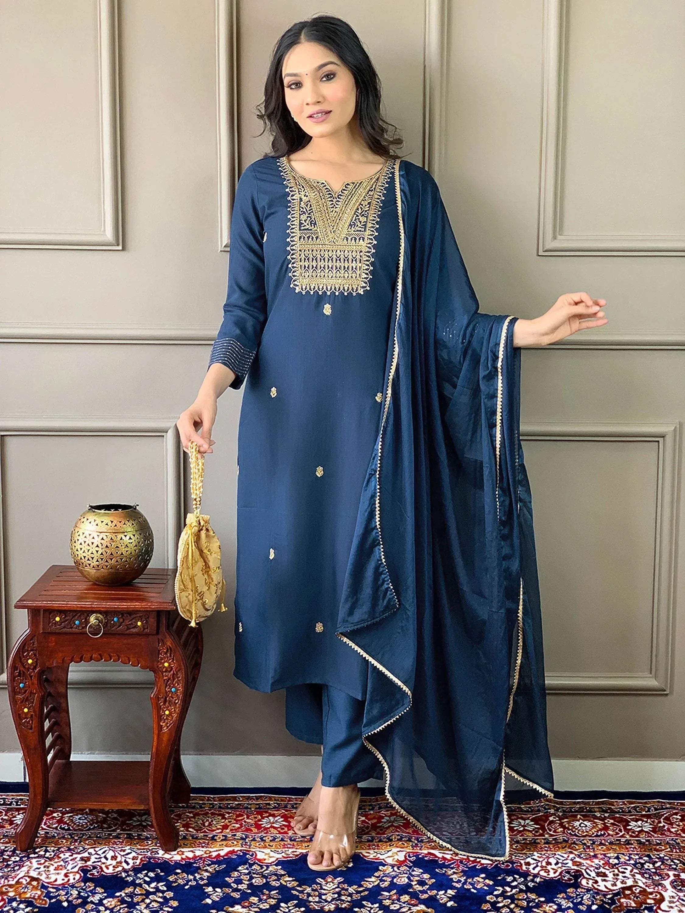 Navy blue embroidered salwar kameez with gold detailing, paired with matching dupatta and potli bag