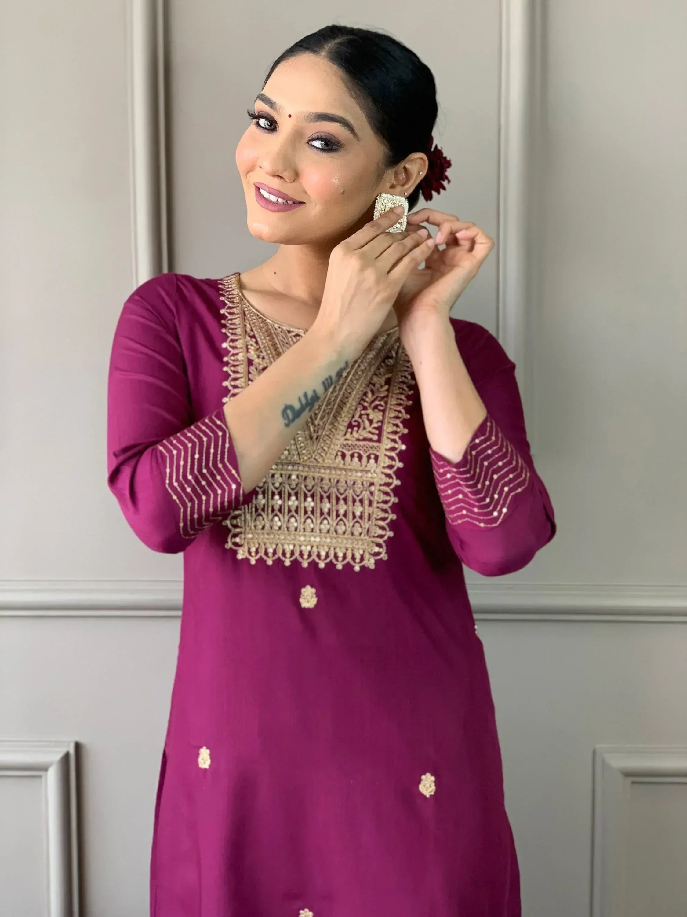 Woman in maroon ethnic kurti with gold embroidery, styling statement earrings for Indian wear