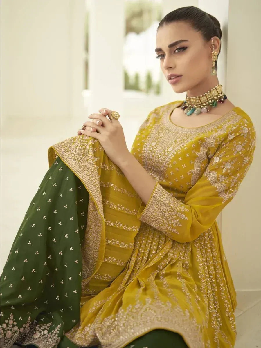 Woman in yellow embroidered ethnic salwar kameez with green dupatta and traditional jewelry