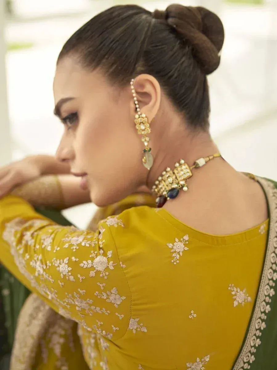 Woman in yellow embroidered ethnic saree blouse with gold jewelry and bun hairstyle