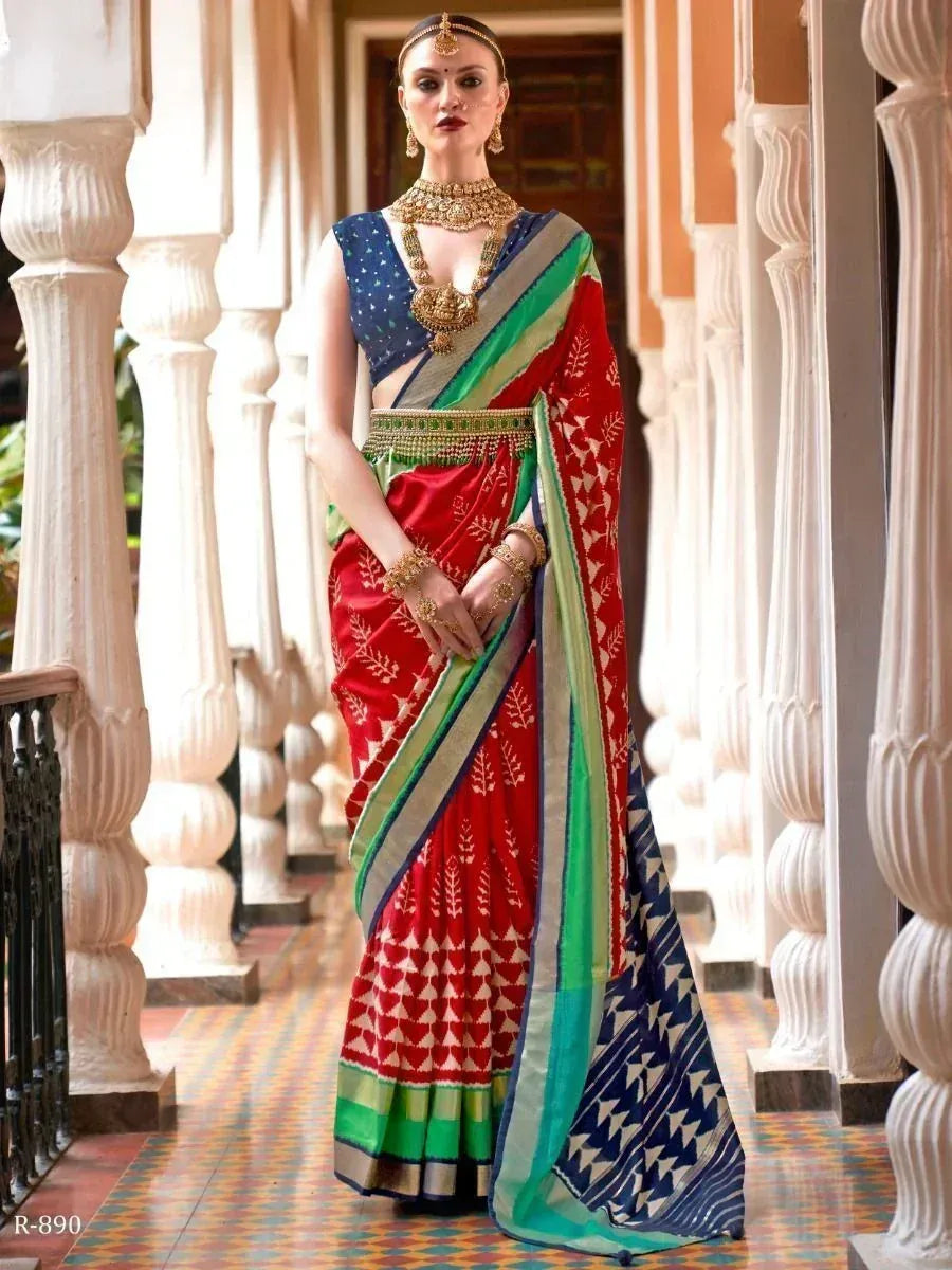 Red and blue printed saree with green border, styled with gold jewelry for ethnic wear