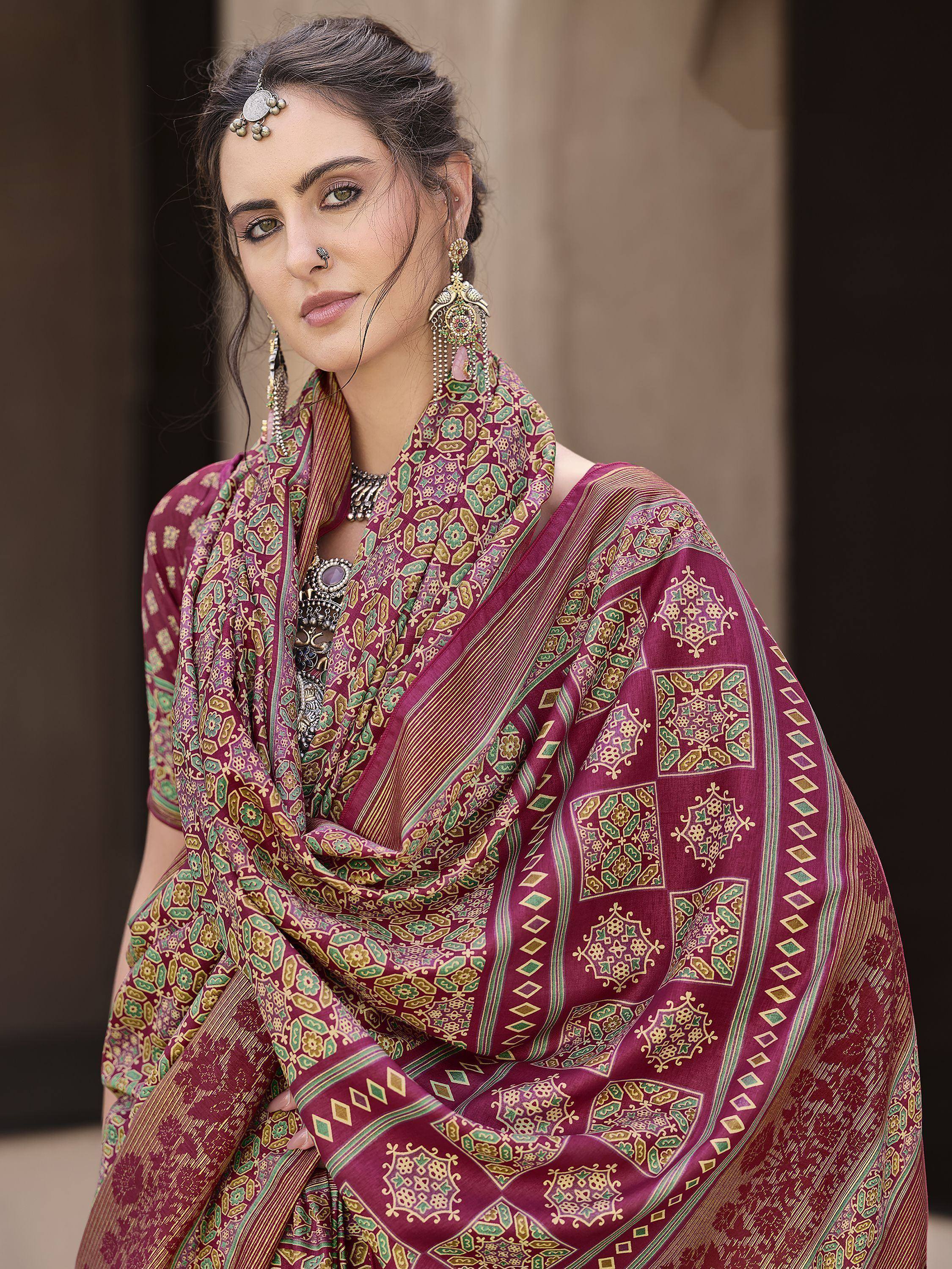 Woman in maroon ethnic saree with green and gold floral print, traditional jewelry, and maang tikka