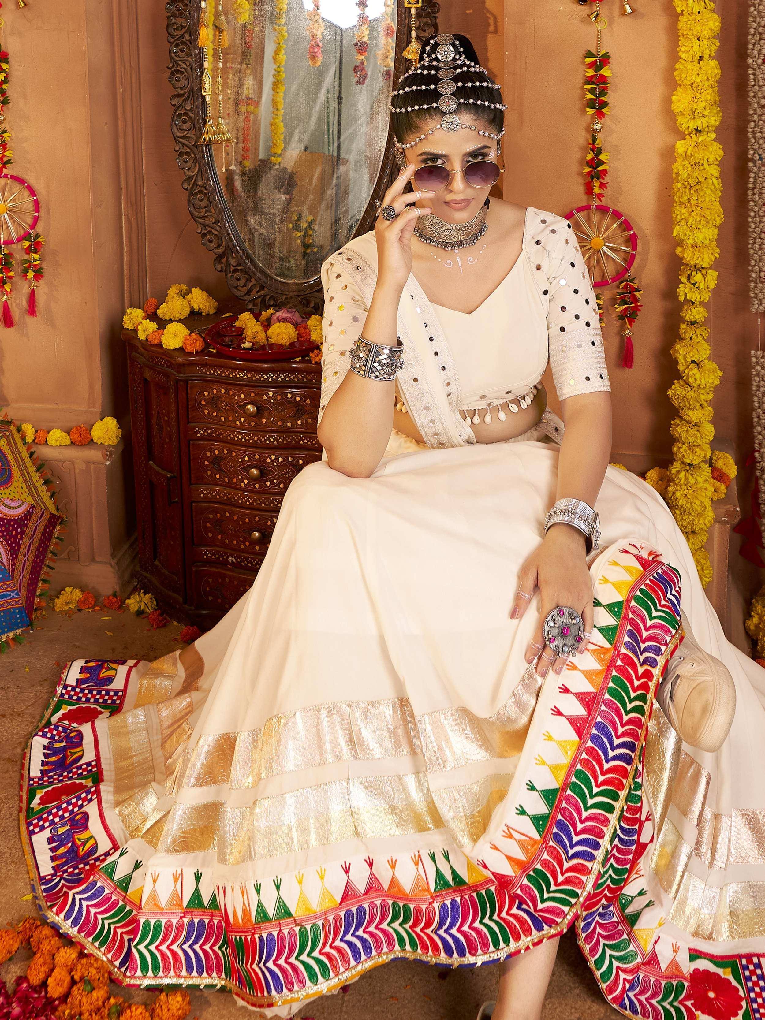 Woman in white embroidered lehenga choli with colorful tribal border, traditional Indian ethnic wear