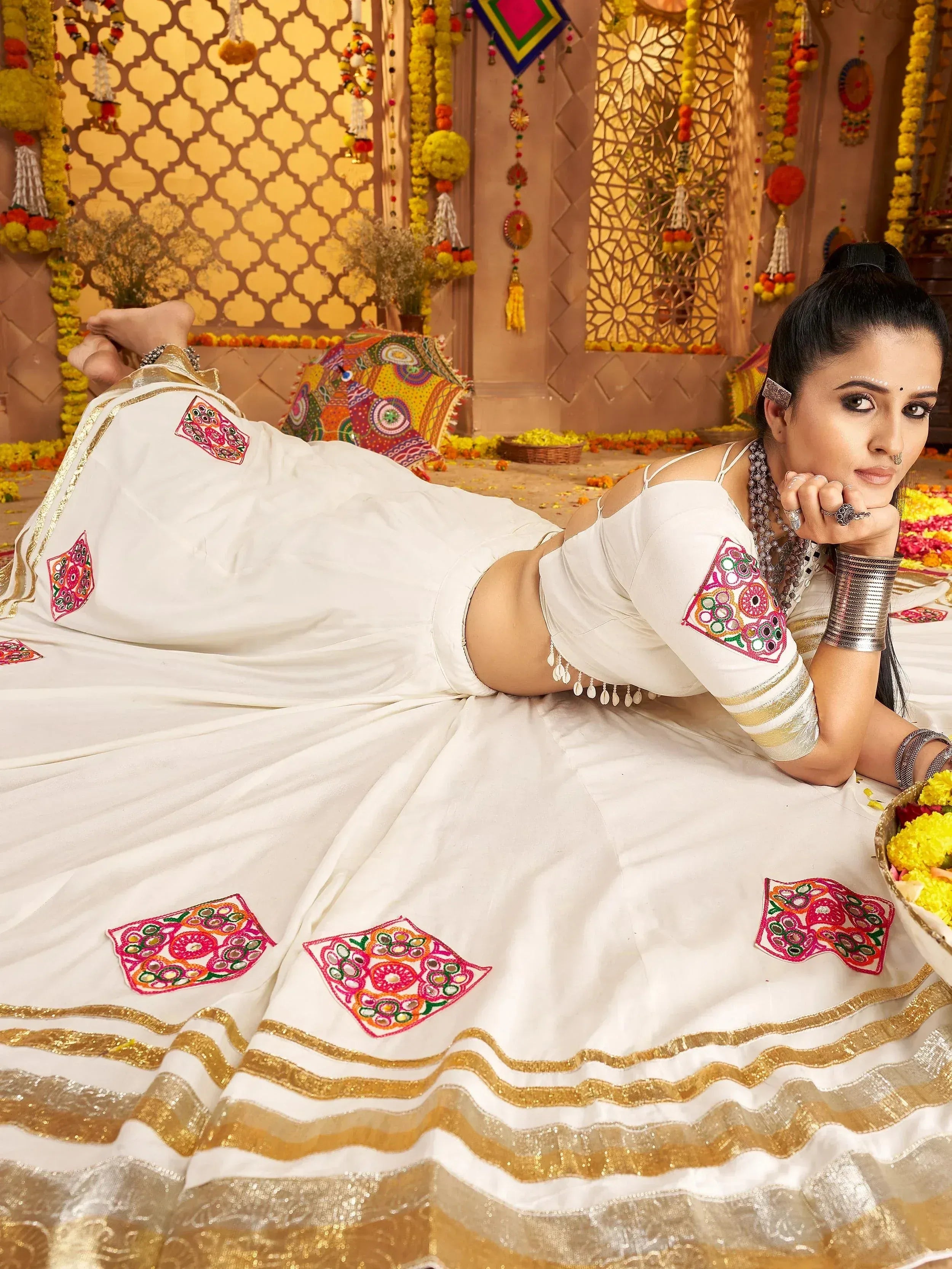 White embroidered lehenga choli with gold trim, floral motifs, and traditional Indian jewelry for festive occasions