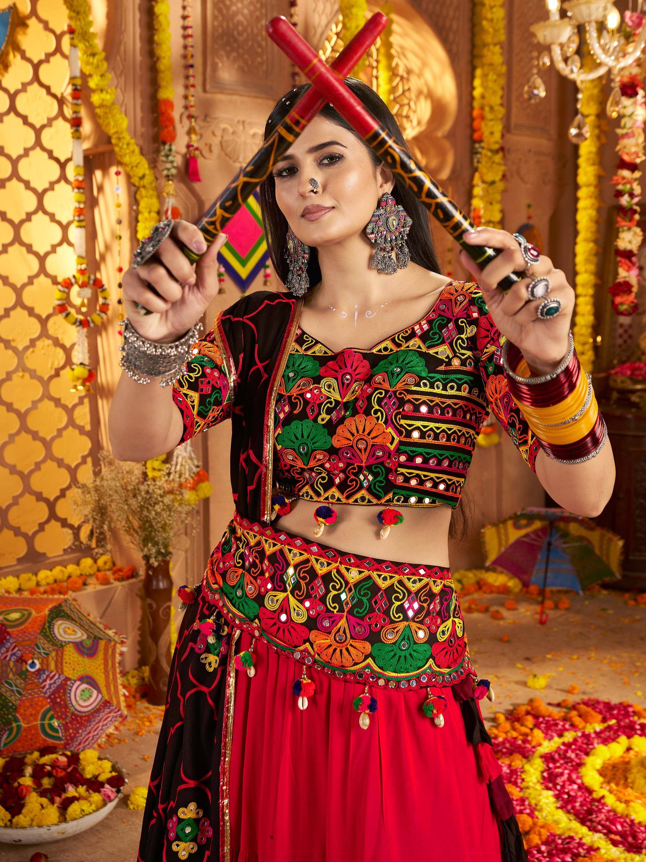 Woman in vibrant Indian ethnic wear with mirror work, holding dandiya sticks for festive celebration