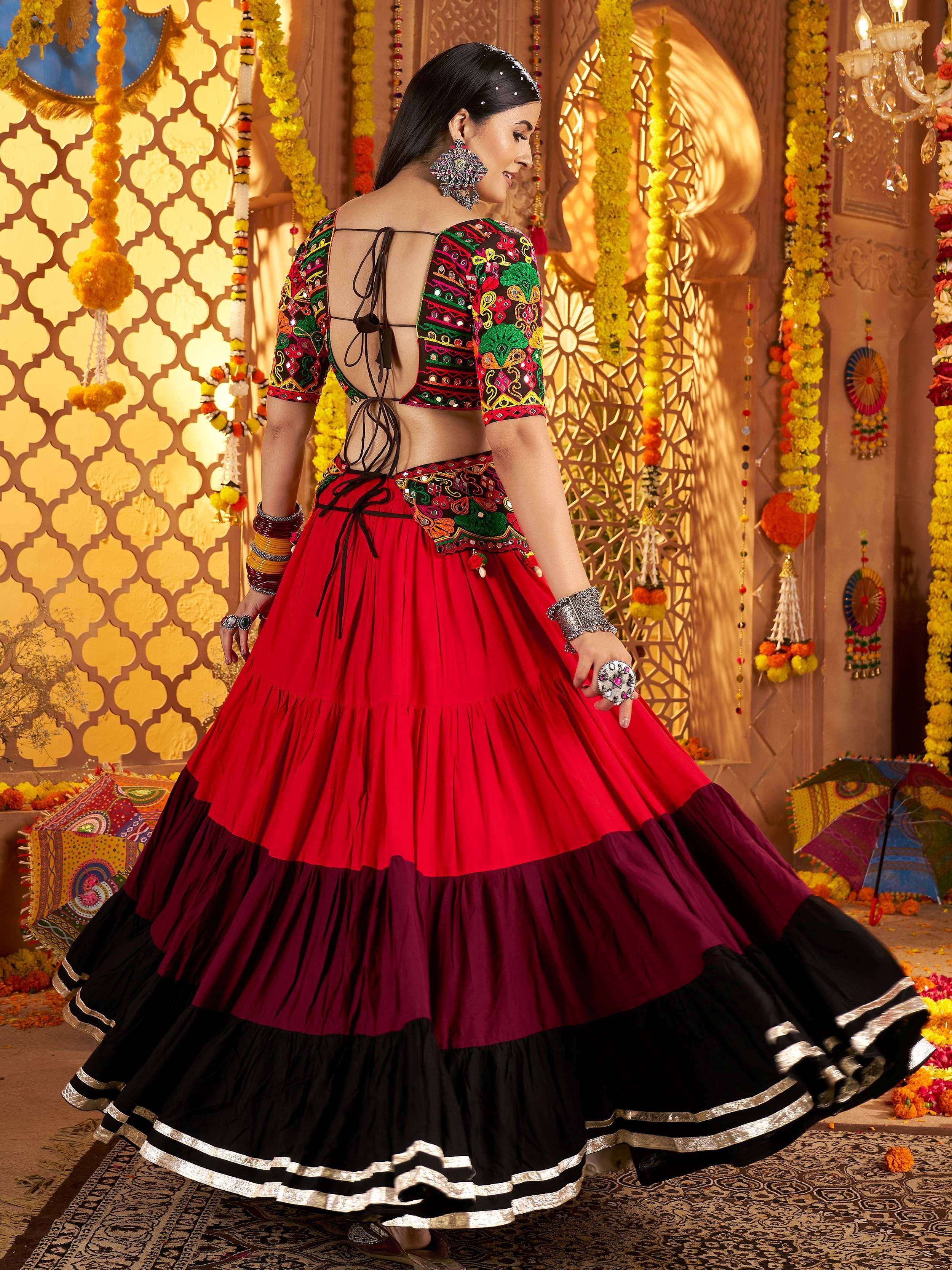 Woman in vibrant red and black embroidered lehenga choli with mirror work, perfect for Indian ethnic celebrations.