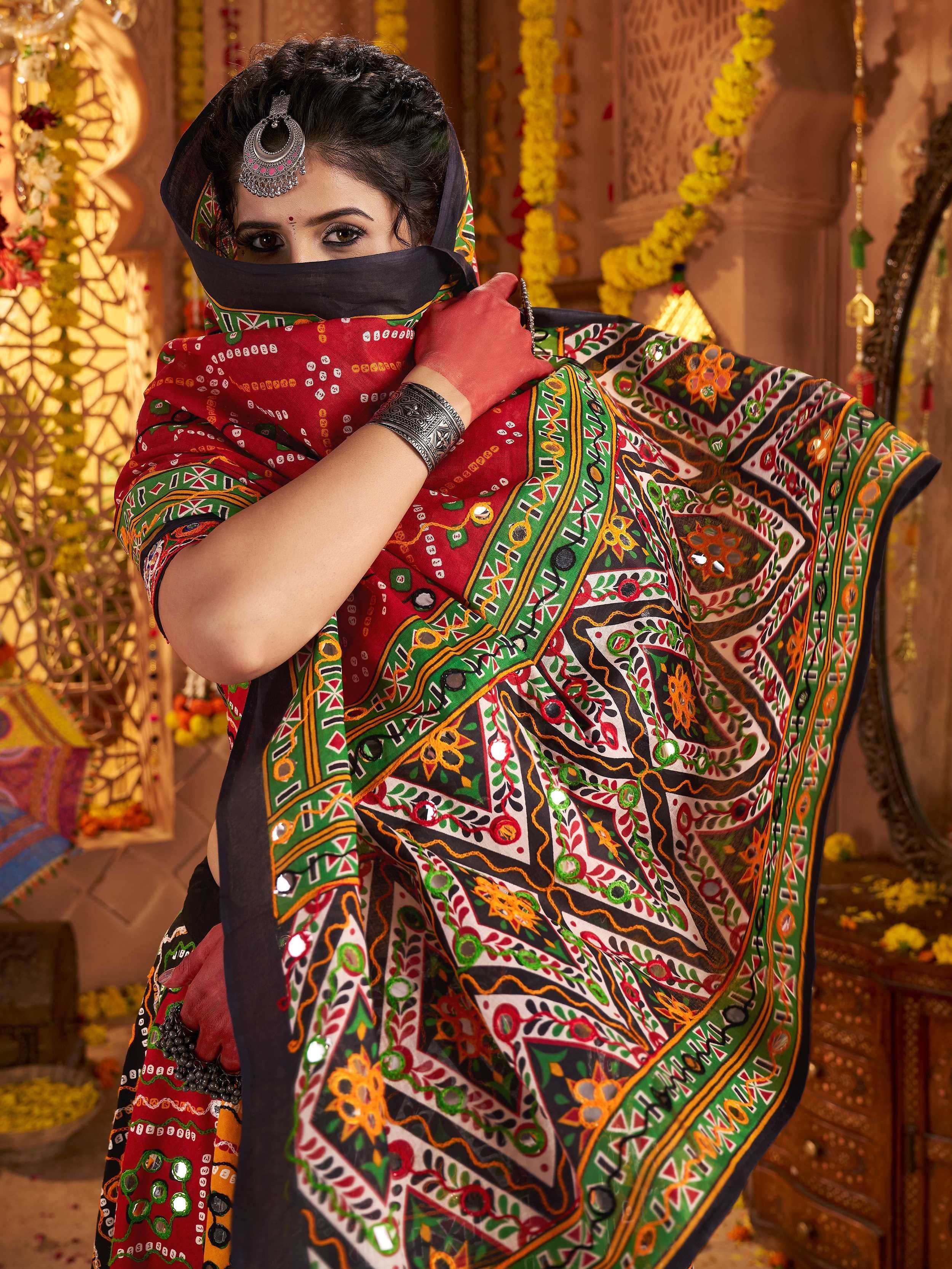 Woman in vibrant red and green embroidered ethnic saree with mirror work, traditional Indian attire