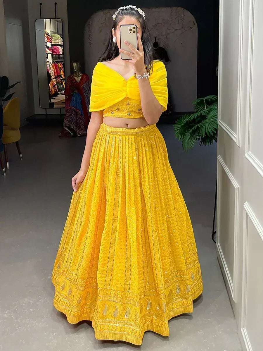 Vibrant yellow designer lehenga choli with embellished skirt and off-shoulder blouse, perfect for Indian ethnic occasions.
