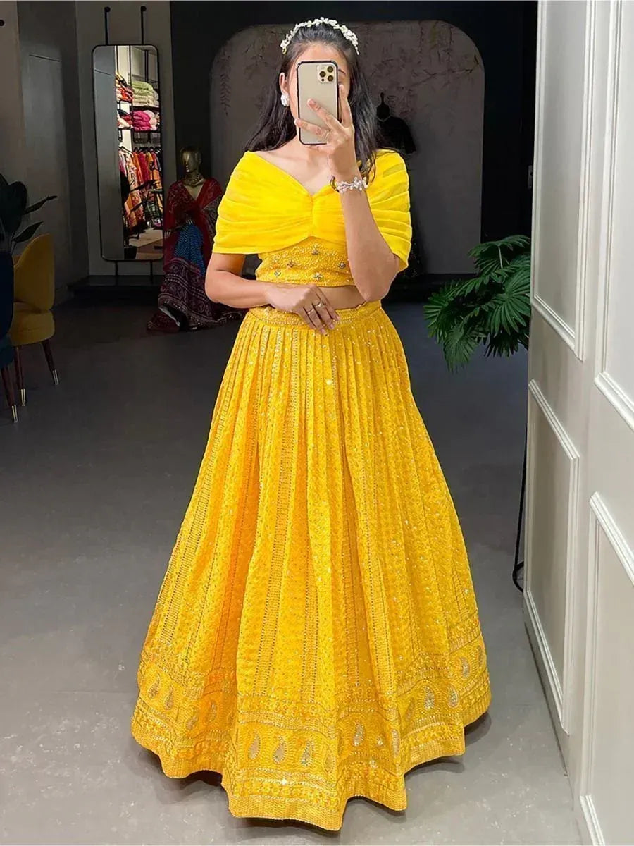 Vibrant yellow designer lehenga choli with embellished skirt and off-shoulder blouse, perfect for Indian ethnic occasions.