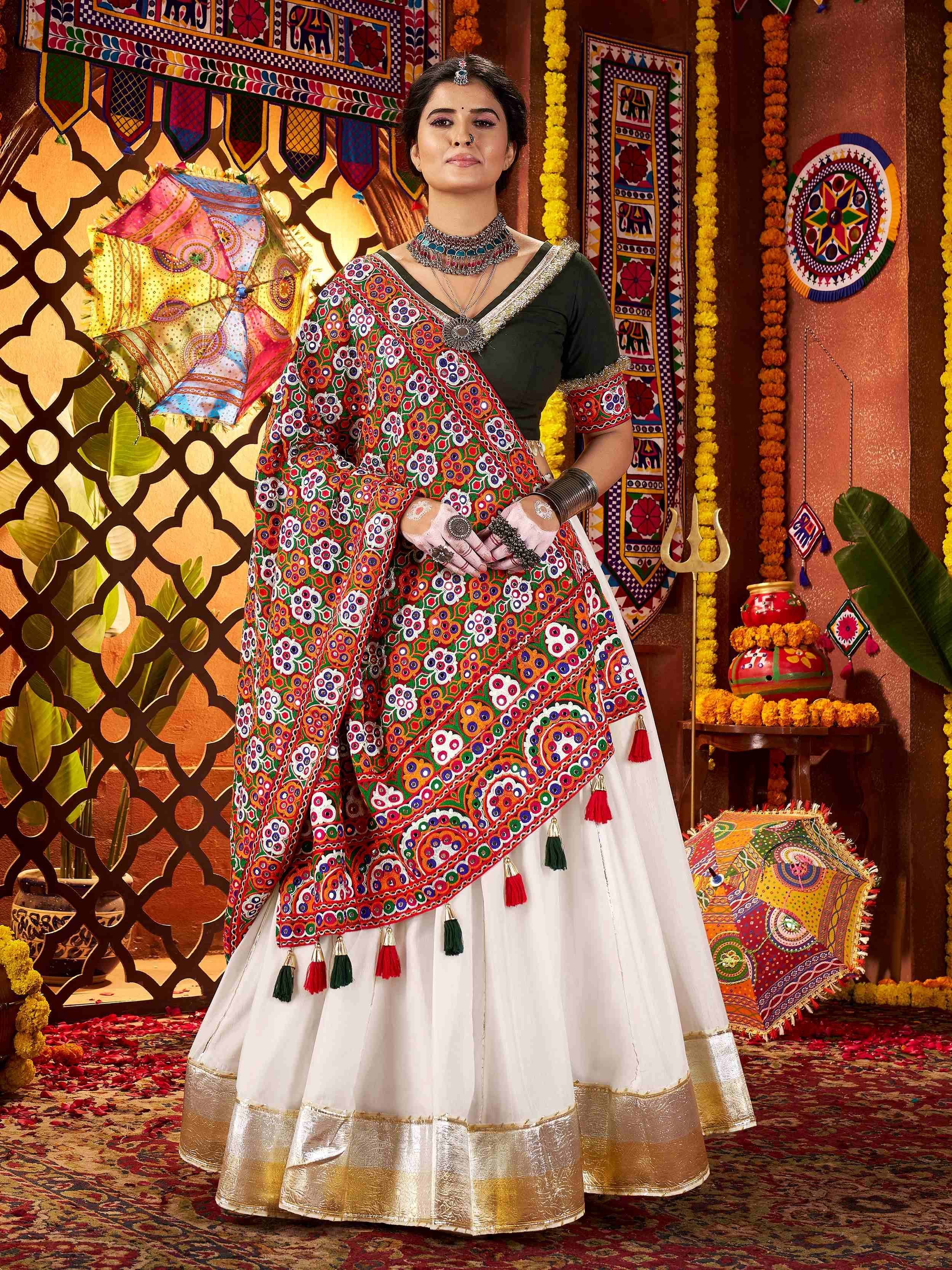 Woman in vibrant embroidered Indian lehenga choli with mirror work, floral patterns, and tassels, styled for festive occasions