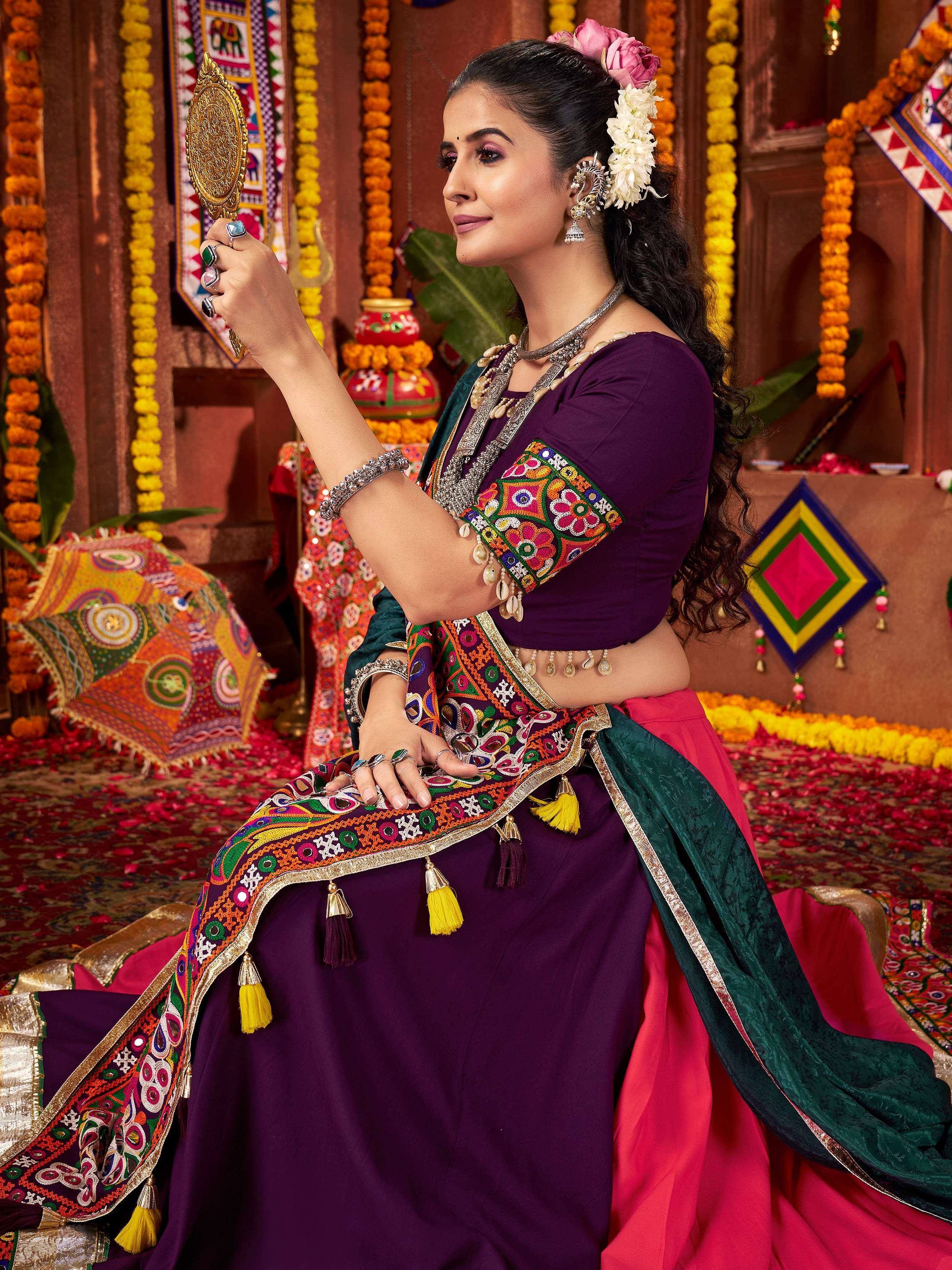 Woman in purple embroidered lehenga choli with mirror, floral hair, traditional Indian ethnic wear