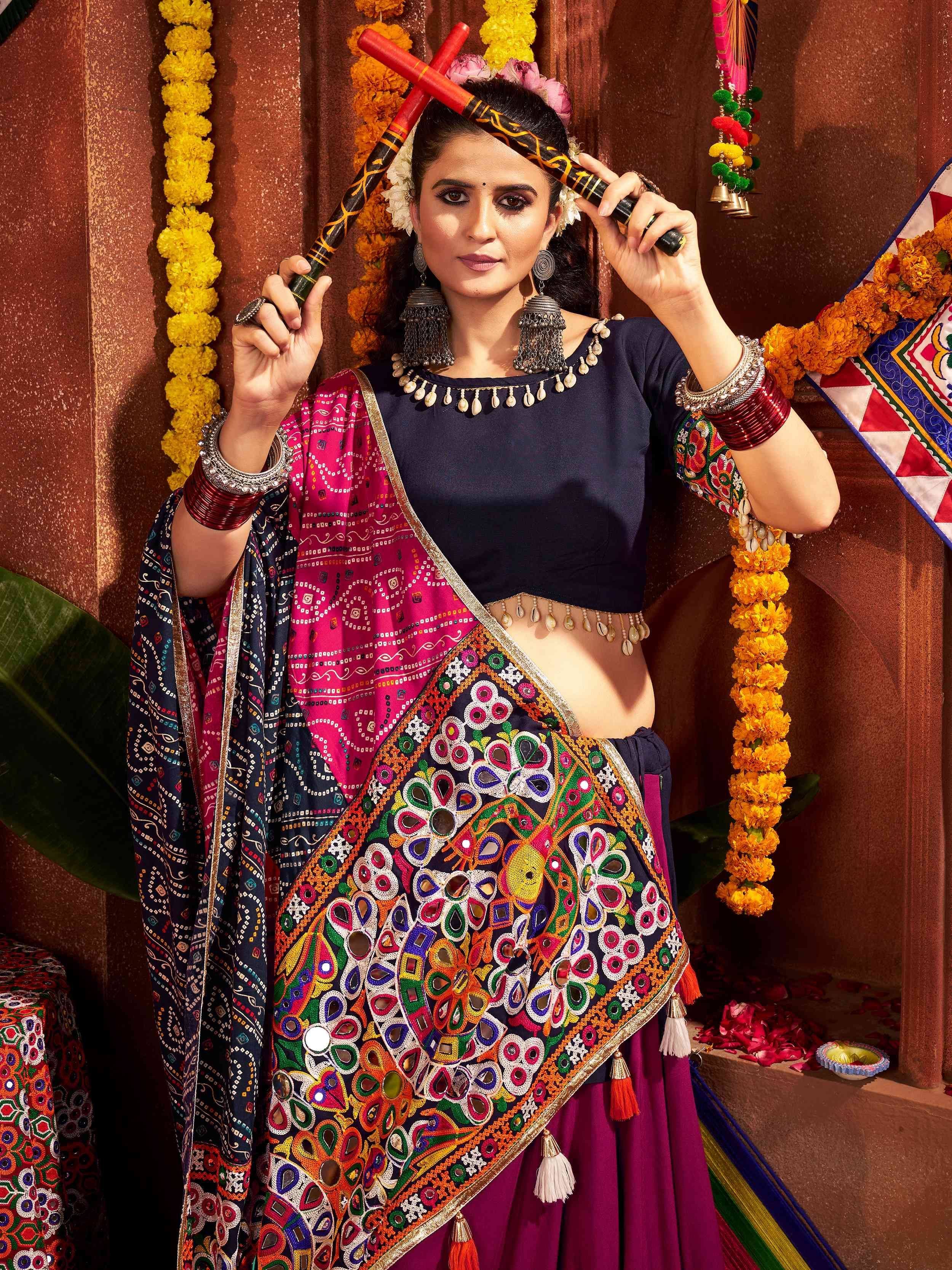 Woman in vibrant embroidered Indian ethnic wear with mirror work and floral garlands