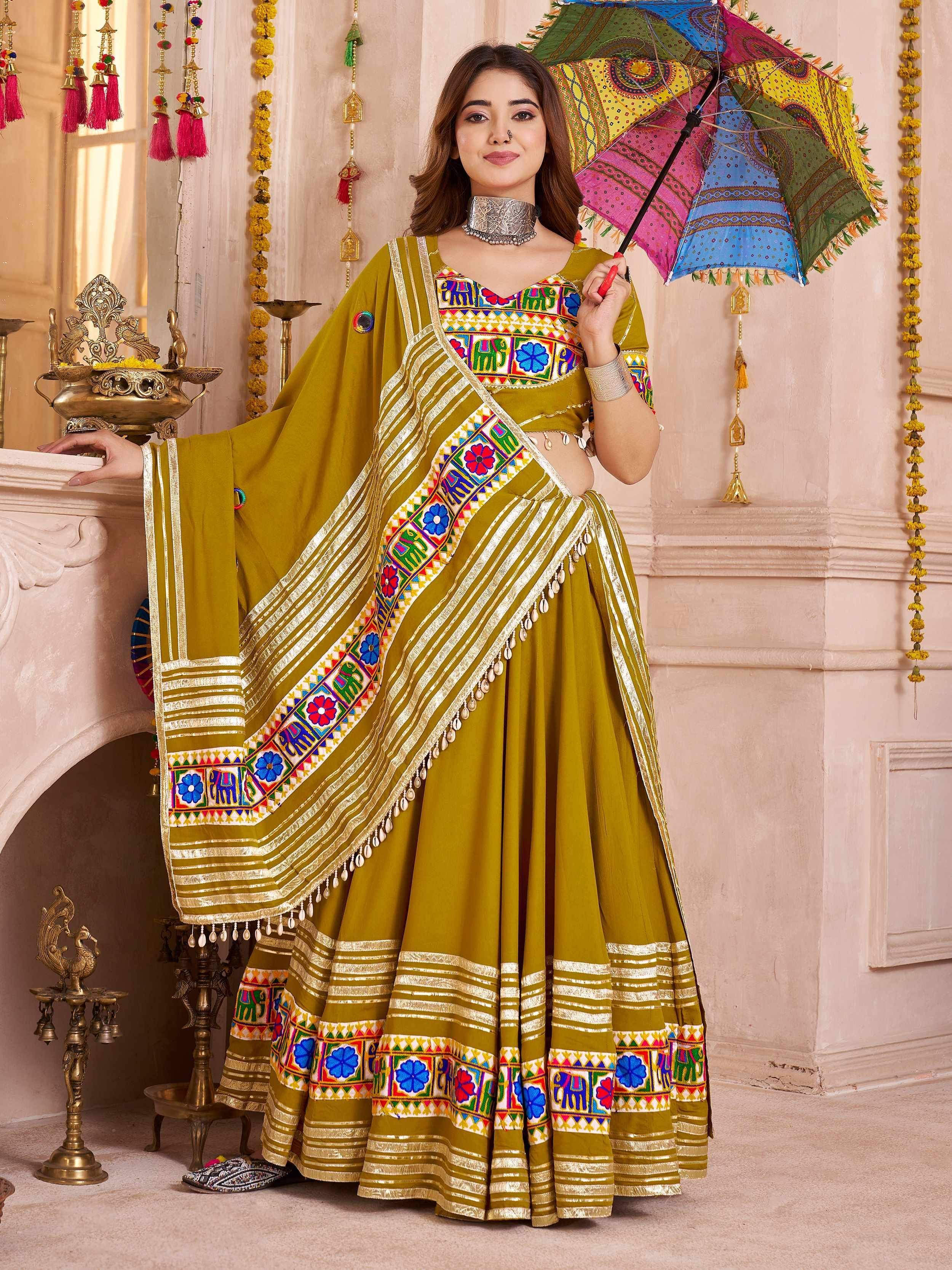 Olive green embroidered lehenga choli with colorful mirror work, paired with a matching dupatta and decorative umbrella.