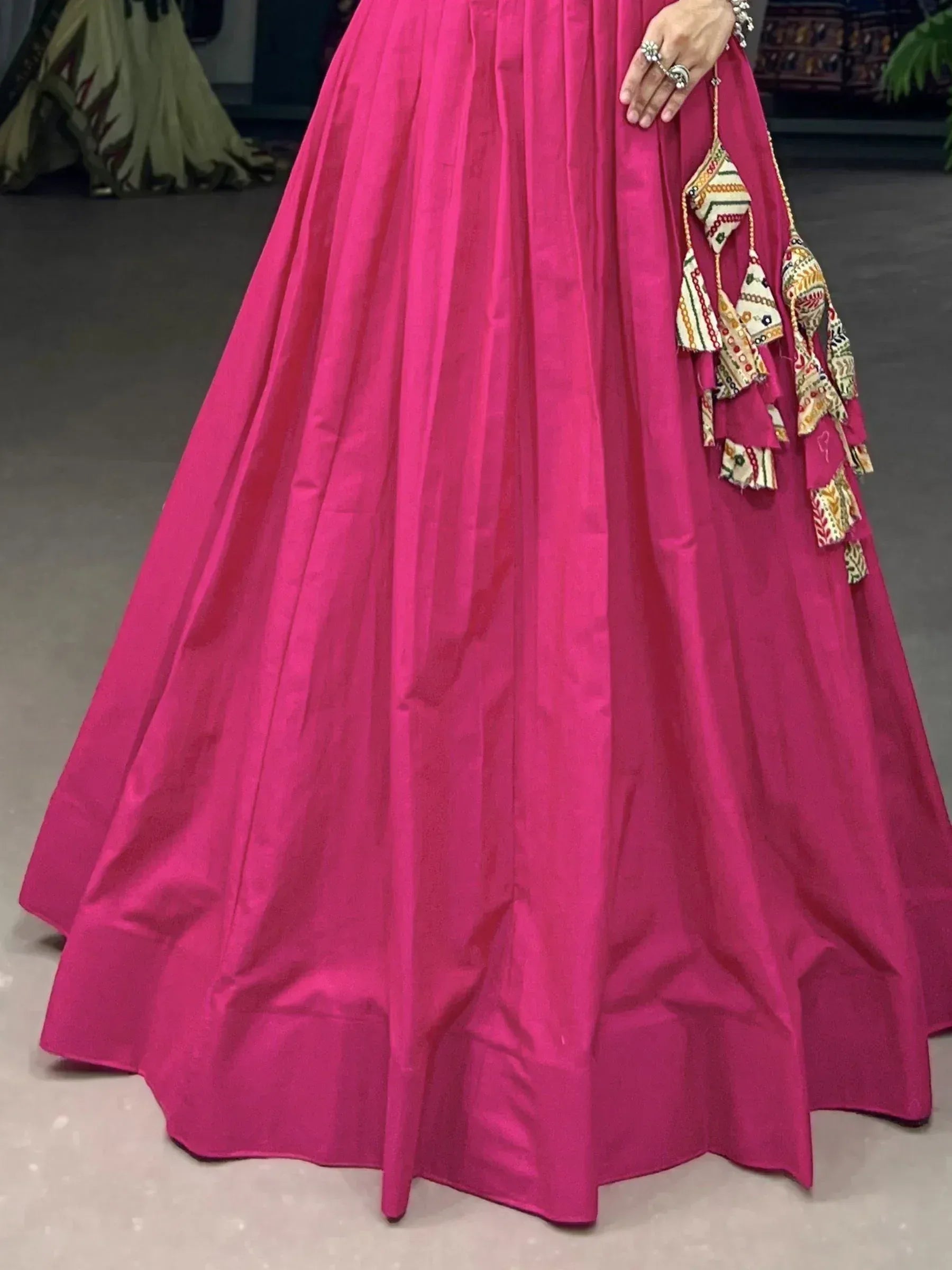 Vibrant pink Indian ethnic gown with embroidered tassels, perfect for festive occasions and weddings.