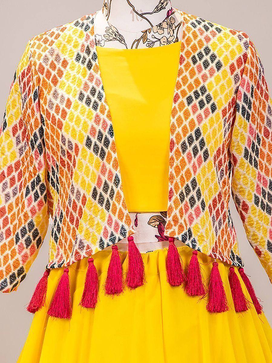 Vibrant yellow ethnic gown with geometric print jacket and pink tassels, perfect for festive occasions.