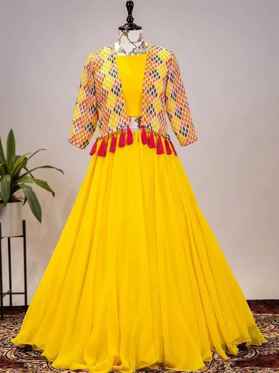 Vibrant yellow ethnic lehenga choli with printed jacket and pink tassels, perfect for festive occasions