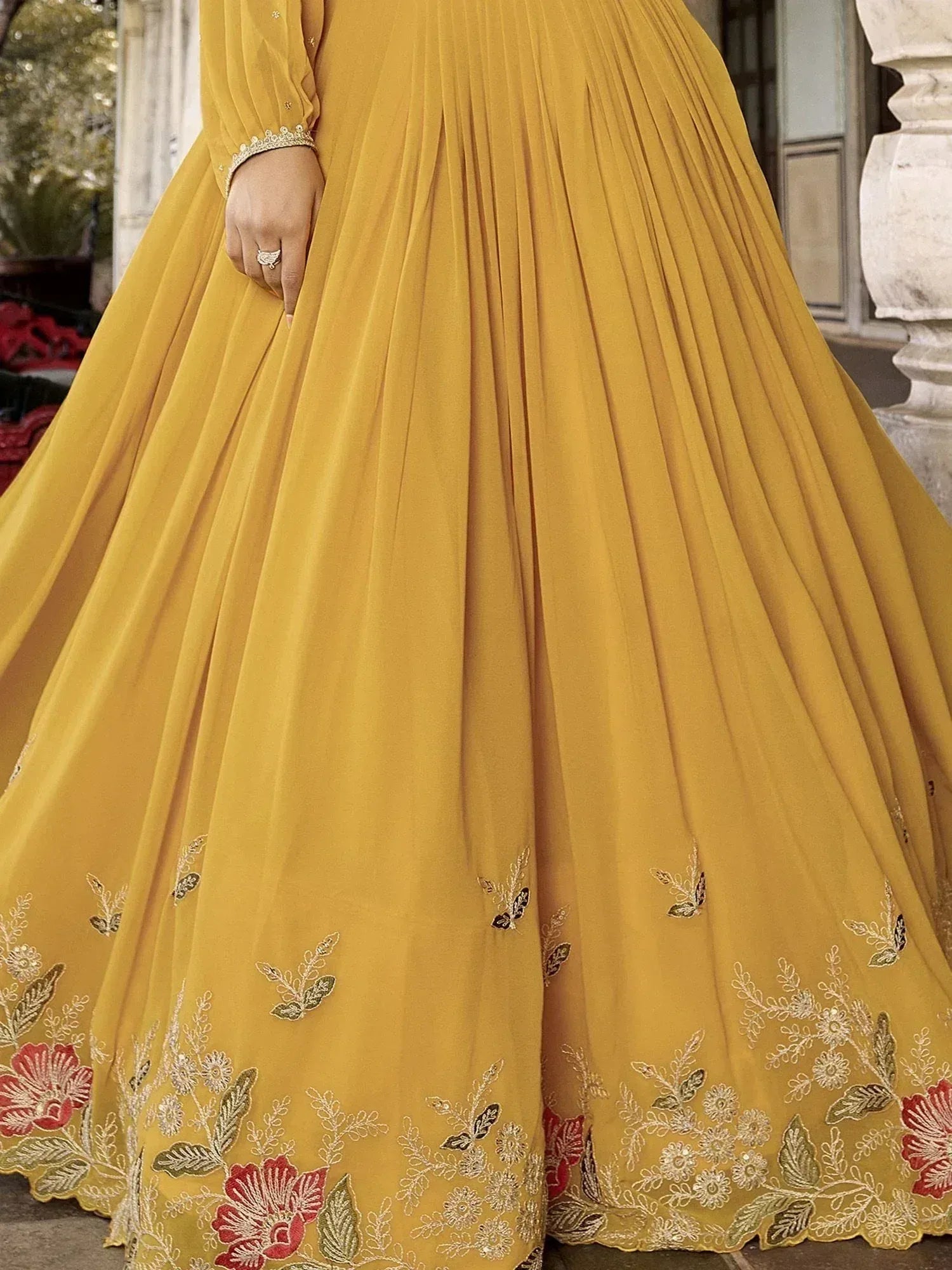 Mustard yellow ethnic gown with floral embroidery and pleated skirt, perfect for Indian weddings and festive occasions.