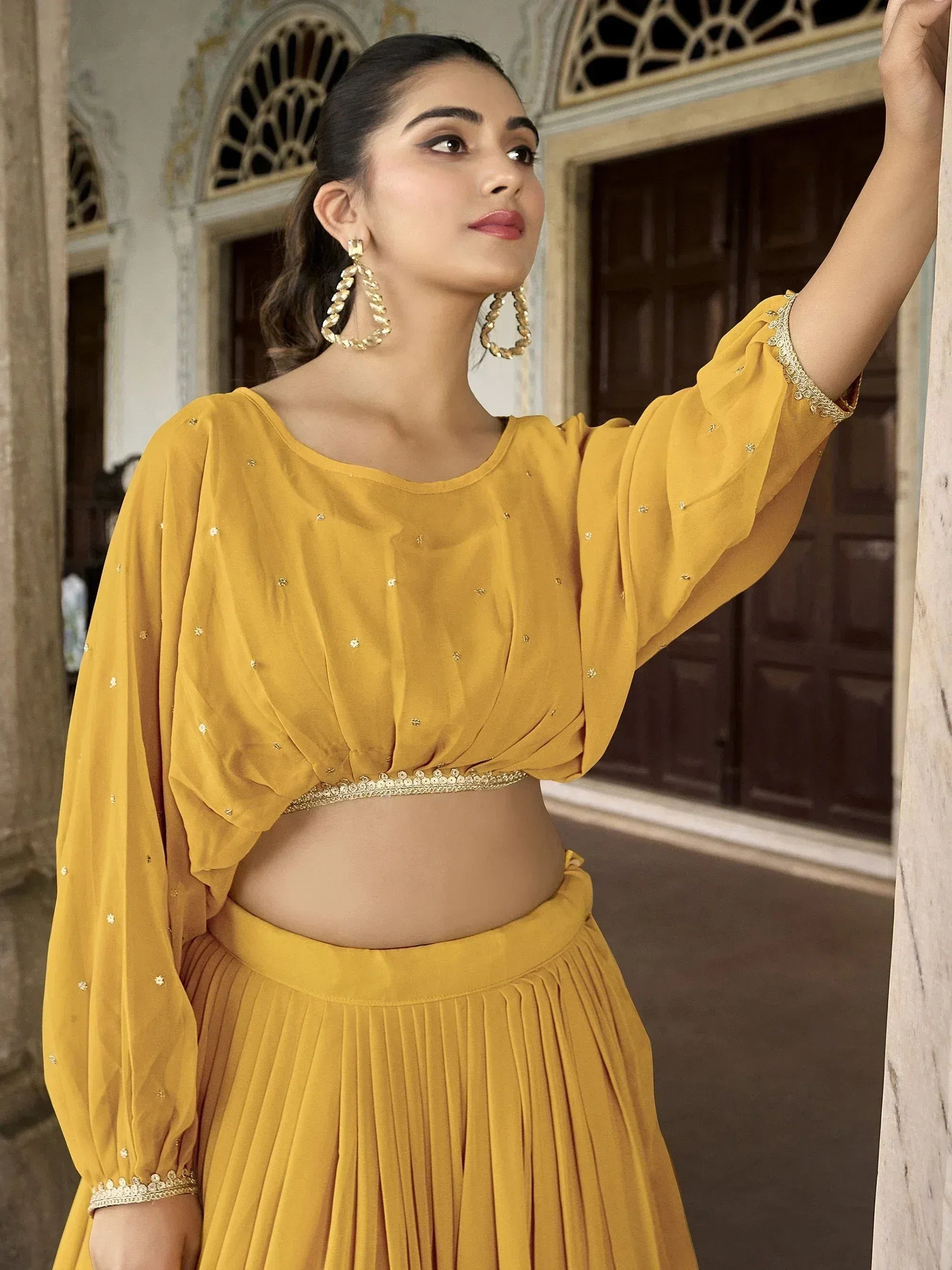 Mustard yellow ethnic lehenga choli with embellished crop top and pleated skirt, perfect for Indian occasions