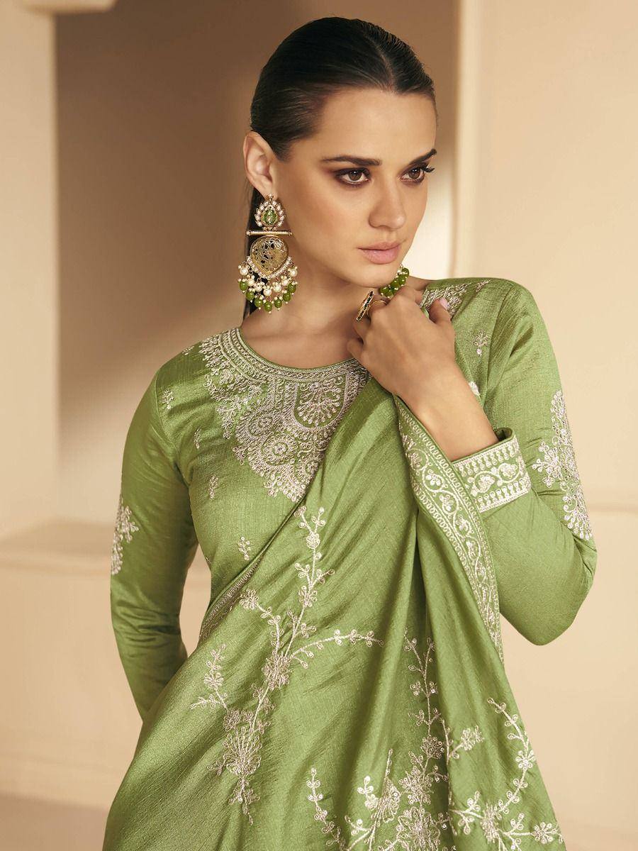 Green embroidered ethnic gown with white floral detailing, paired with statement earrings for festive occasions.