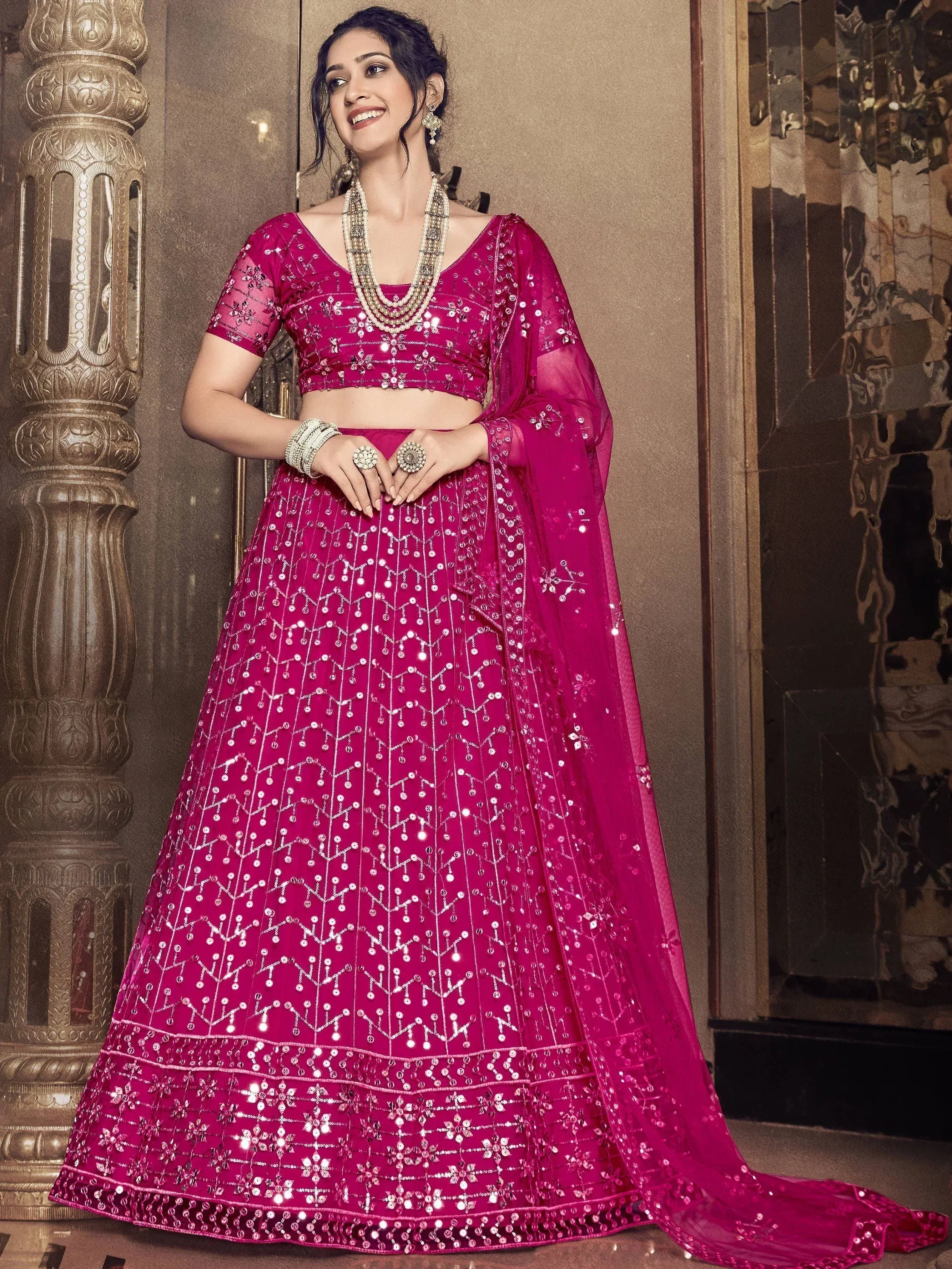 Fuchsia pink designer lehenga choli with heavy mirror and sequin work, perfect for Indian weddings and festive occasions.