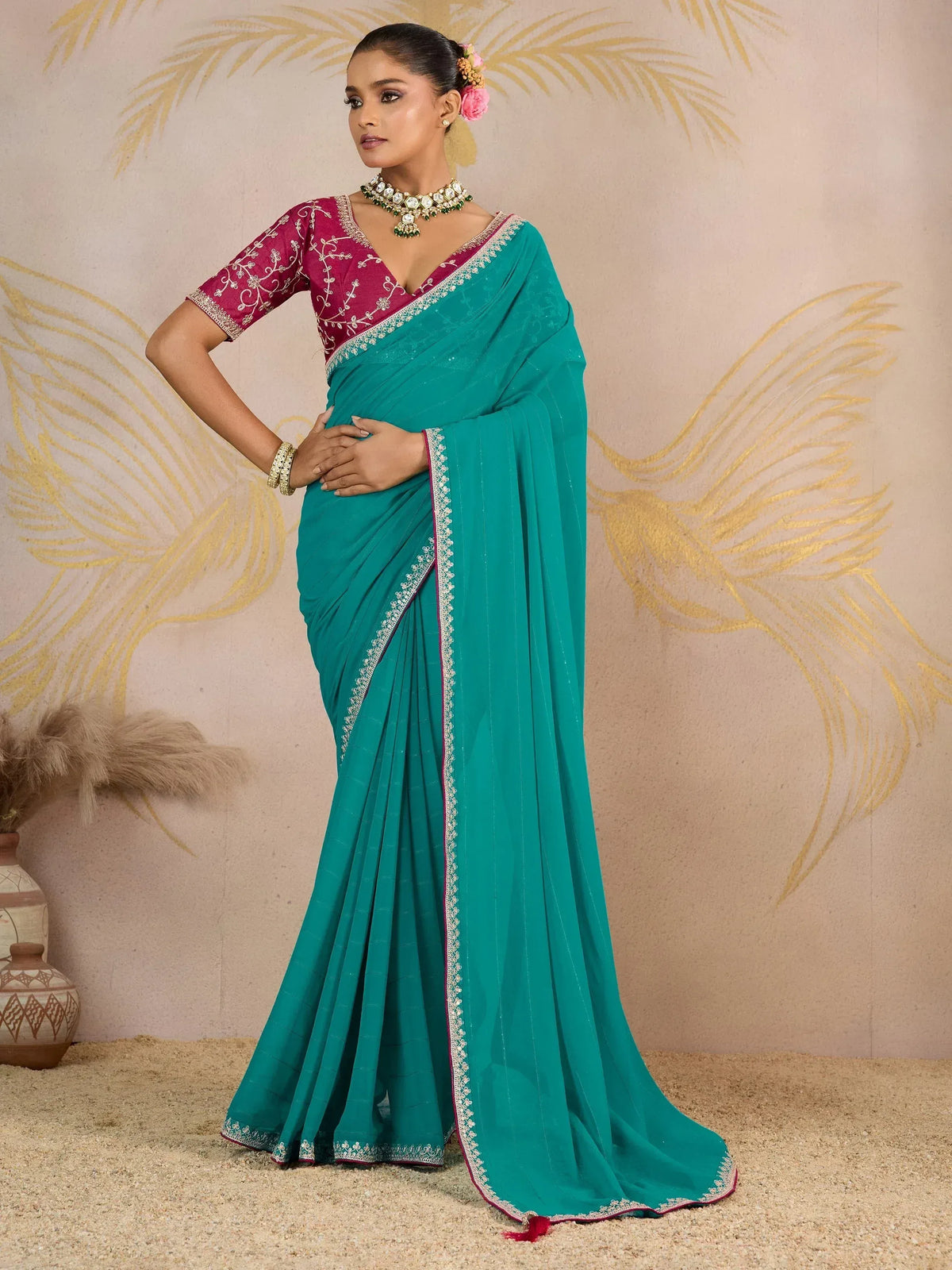 Teal saree with embroidered border and maroon blouse, styled with traditional jewelry