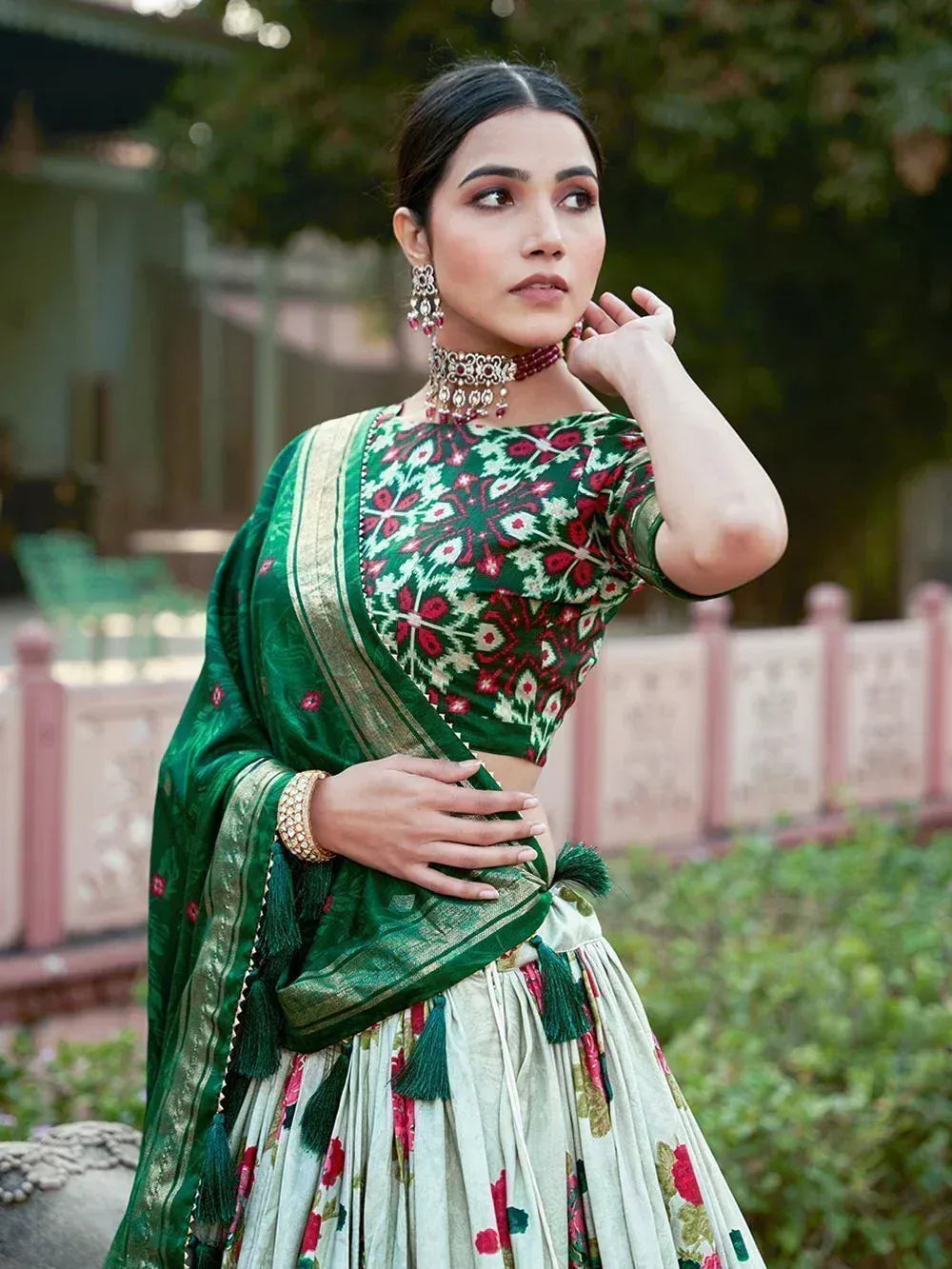 Green floral lehenga choli with gold border and tassels, perfect for Indian ethnic wear occasions.
