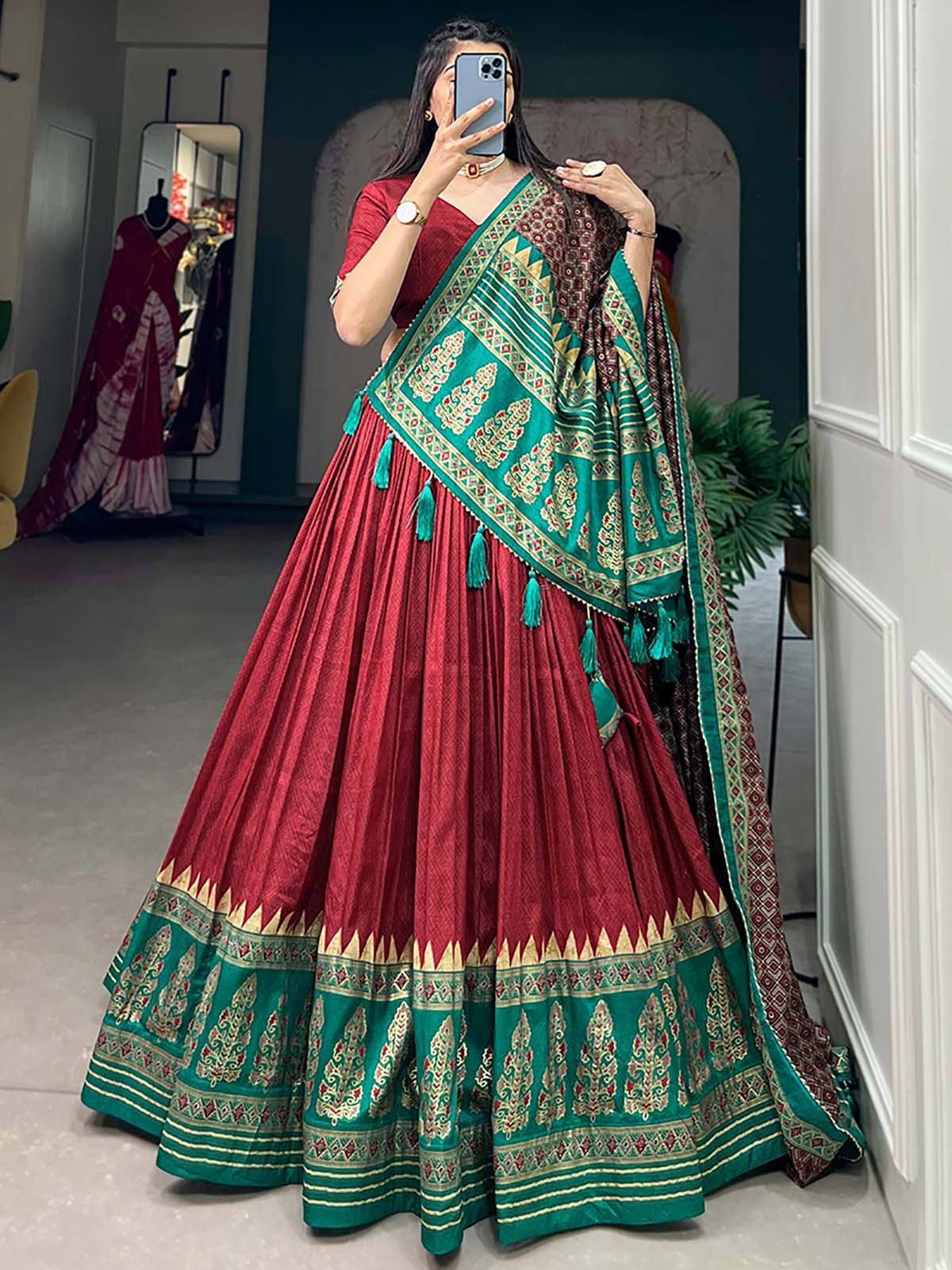 Red and green designer lehenga choli with intricate embroidery and tassels, perfect for Indian ethnic wear occasions.