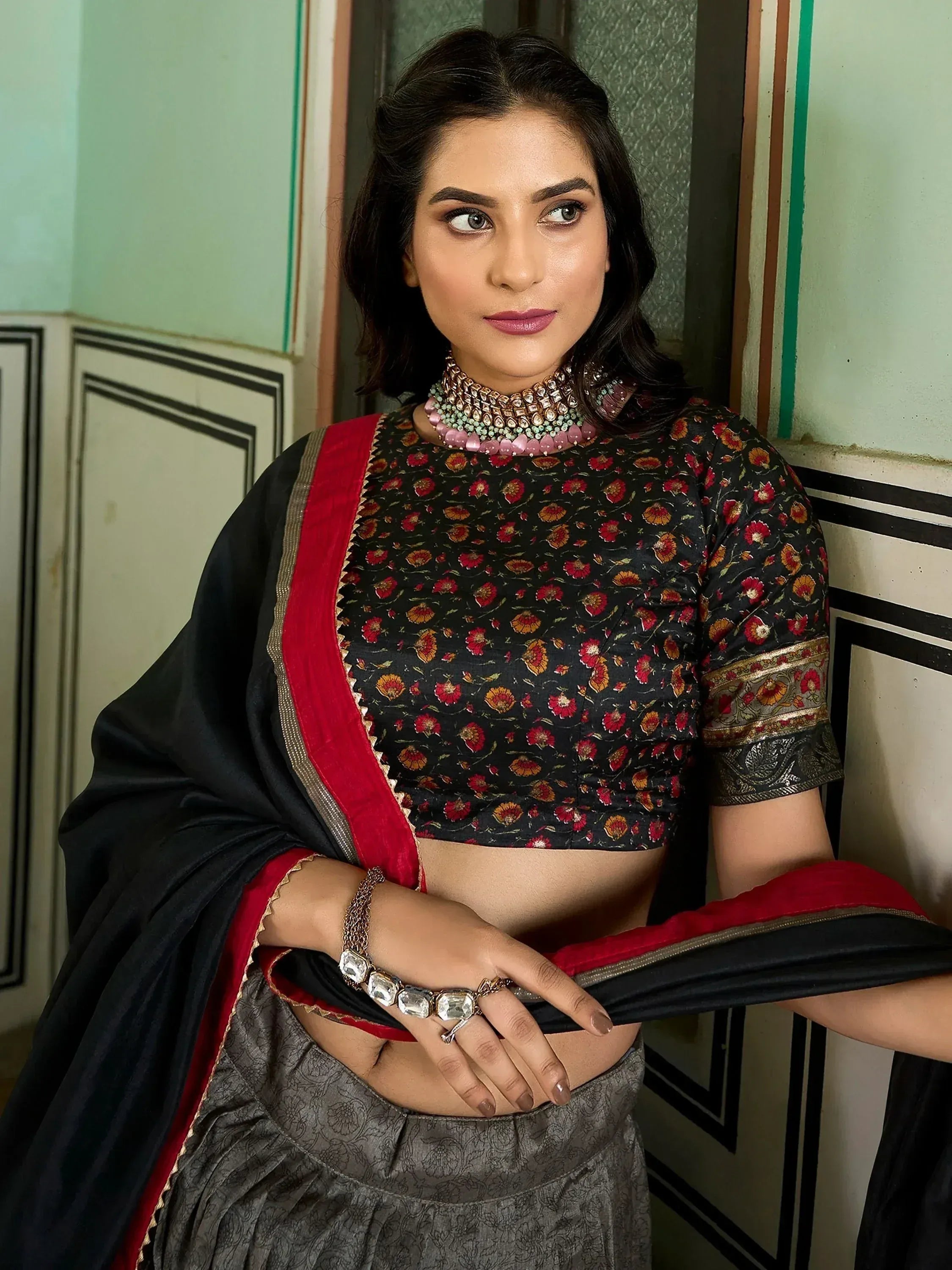 Woman in black floral blouse with red border, grey lehenga, and statement jewelry for Indian ethnic wear