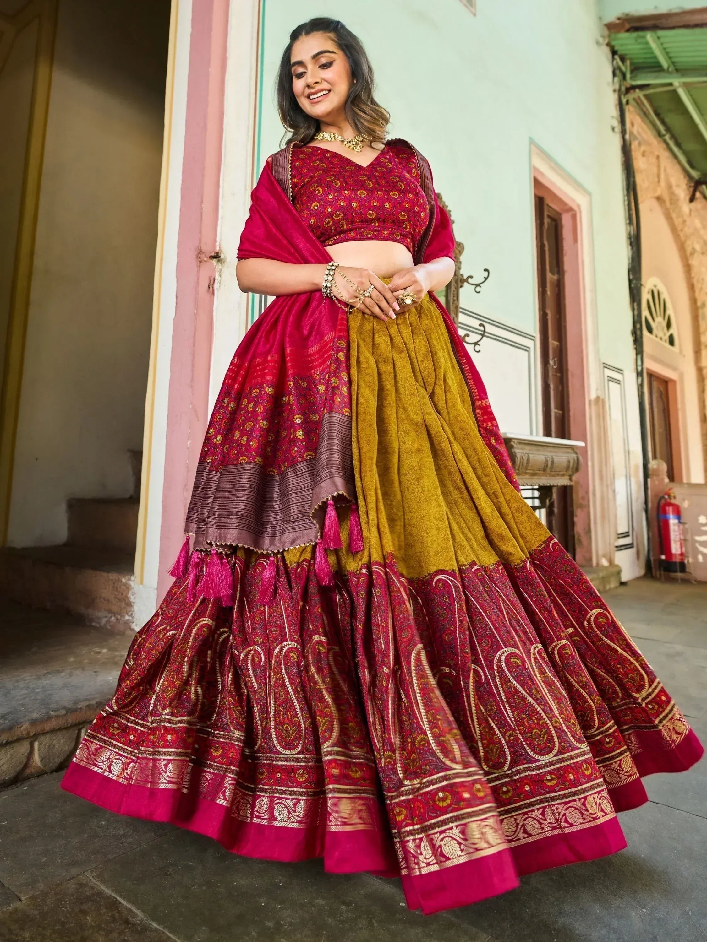 Woman in maroon and mustard designer lehenga choli with paisley print and tassels, ethnic Indian wear