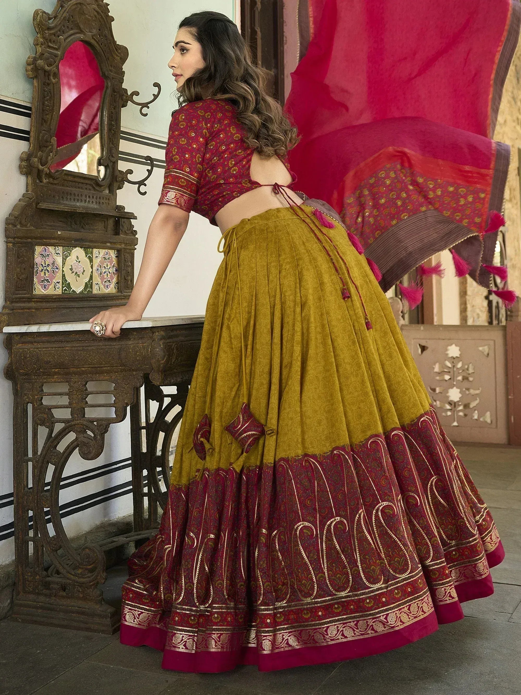 Woman in maroon and mustard designer lehenga choli with paisley border, ethnic Indian wear