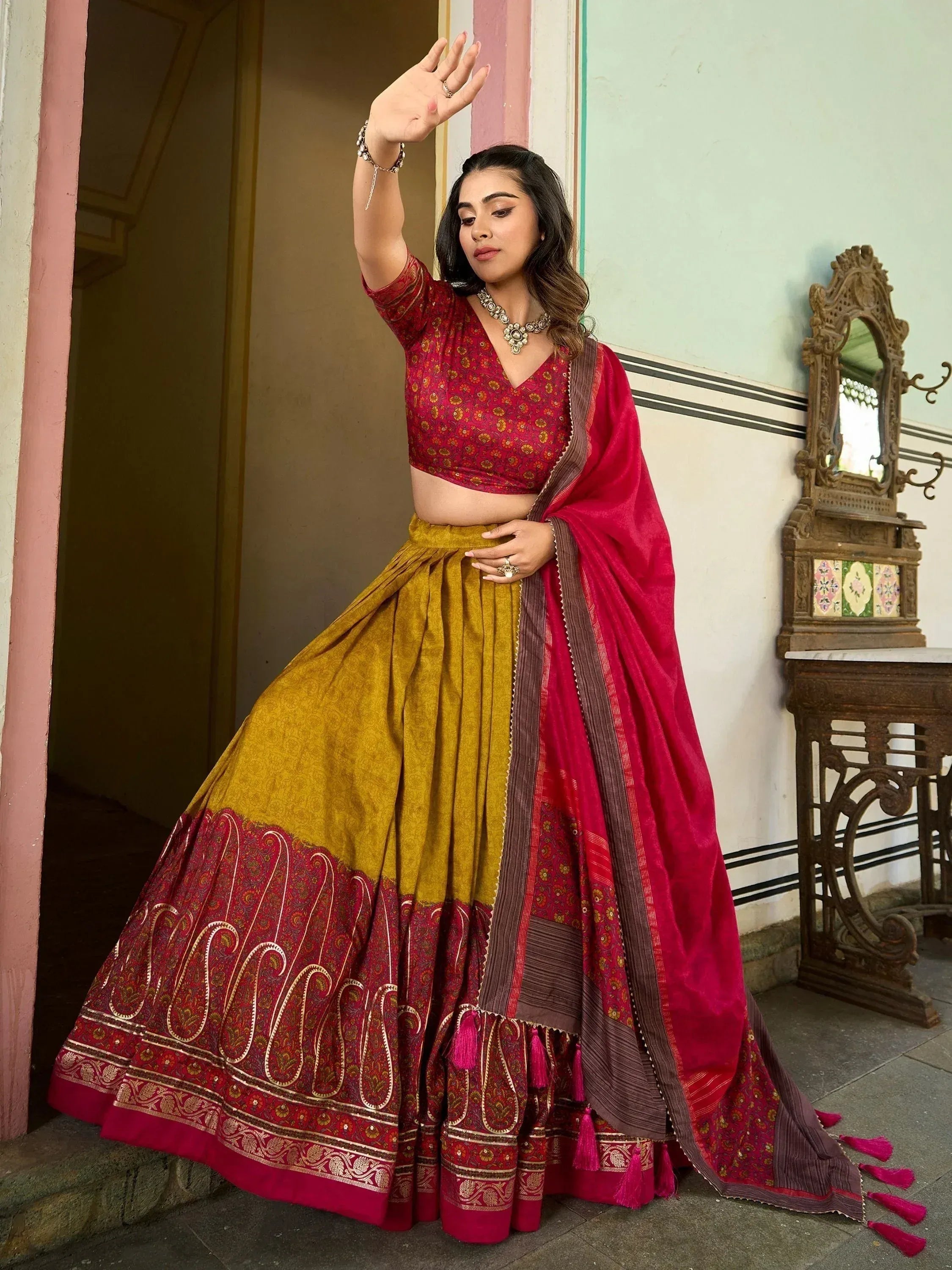 Woman in red and gold designer lehenga choli with intricate paisley border, ethnic wear for weddings