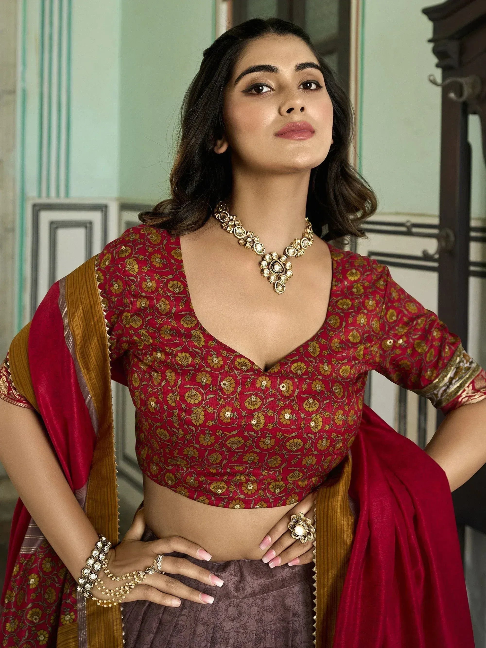 Woman in red floral blouse and purple lehenga with gold jewelry, Indian ethnic wear