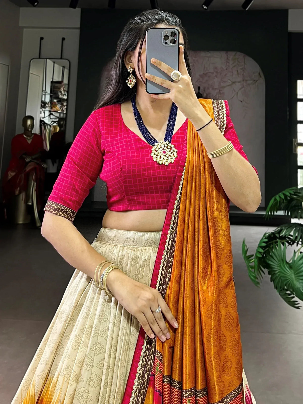 Woman in pink blouse and orange saree with gold jewelry, showcasing ethnic Indian wear