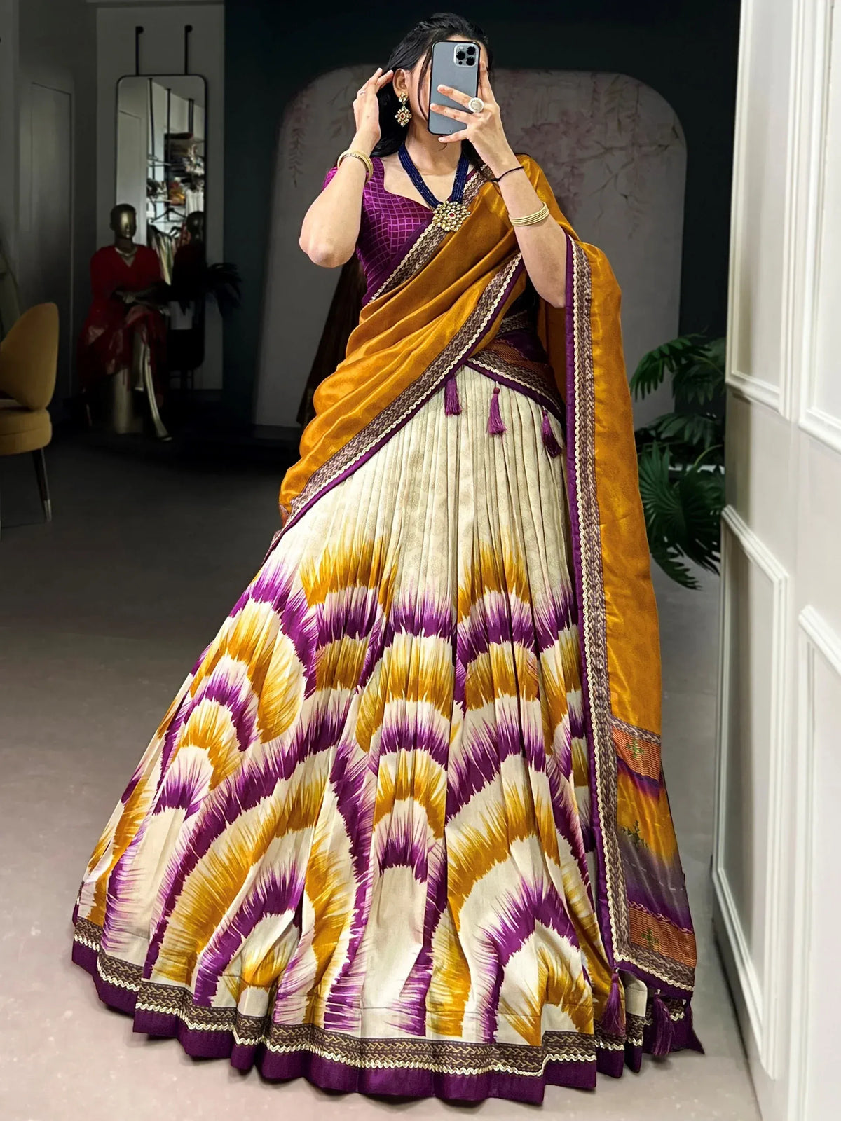 Woman in vibrant purple and gold lehenga choli with ikat print, perfect for Indian ethnic wear occasions.