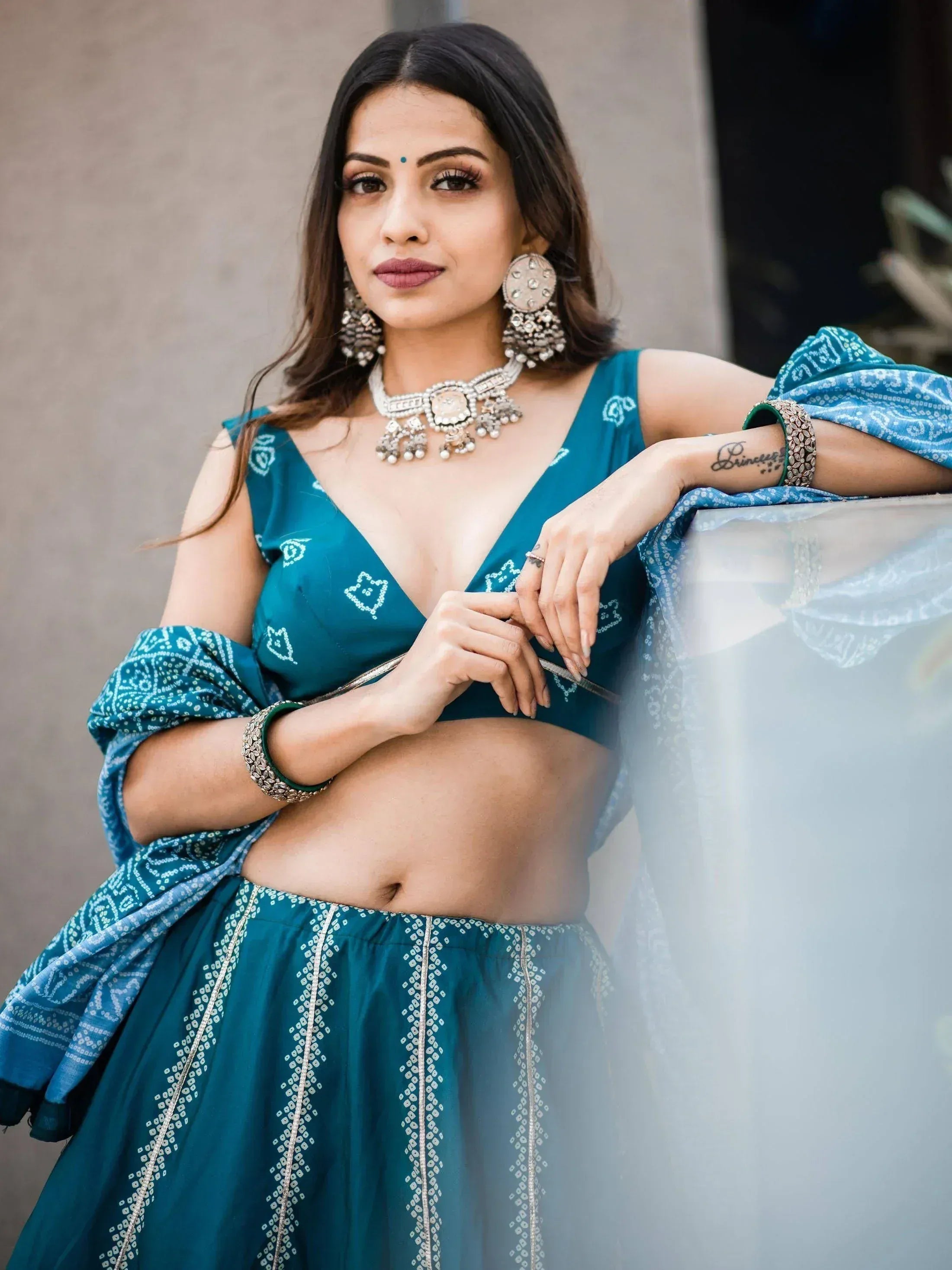 Teal bandhani lehenga choli with silver embroidery, statement jewelry, and dupatta for Indian ethnic wear