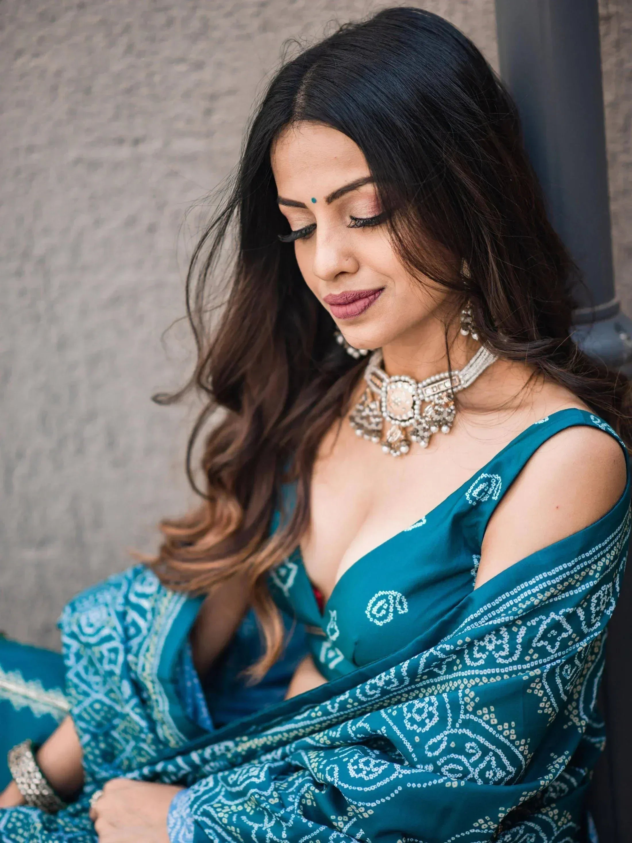 Woman in teal ethnic saree with cold shoulder blouse and traditional jewelry